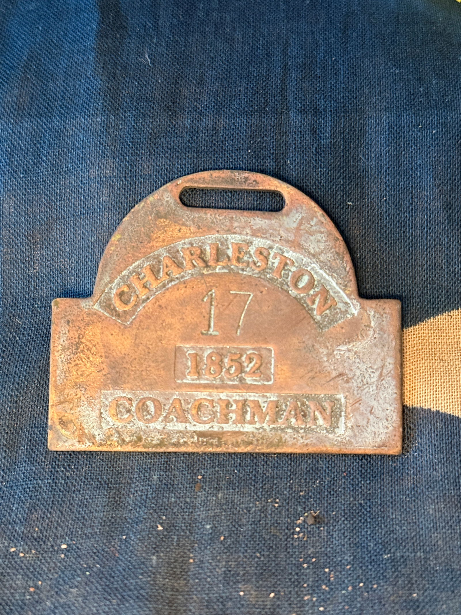 1852 Slave Hire Badge for a Coachman, Charleston, South Carolina Slave Tag: This brass badge is stamped “CHARLESTON / 17 / 1852 / COACHMAN.” It was issued by the city of Charleston, South Carolina, as part of a municipal licensing system regulating enslaved laborers w
