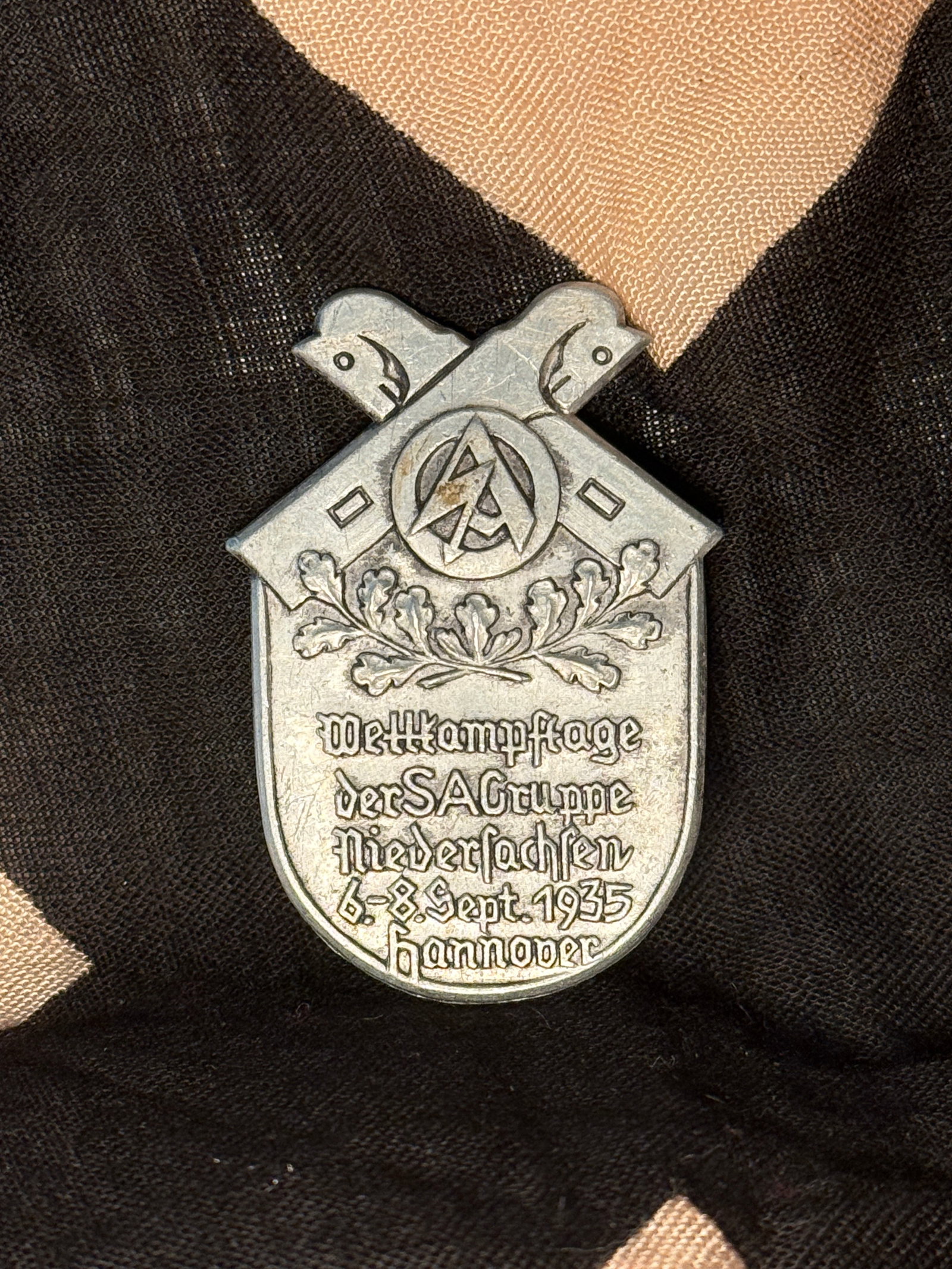 WW2 SA Group Niedersachsen Wehrkampftage Day Badge (“Tinnie??), Hannover, 1935: This stamped metal German day badge, commonly known as a “tinnie,” commemorates the Wehrkampftage (military competition days) of SA Group Niedersachsen, held in Hannover from 6–8 September 1