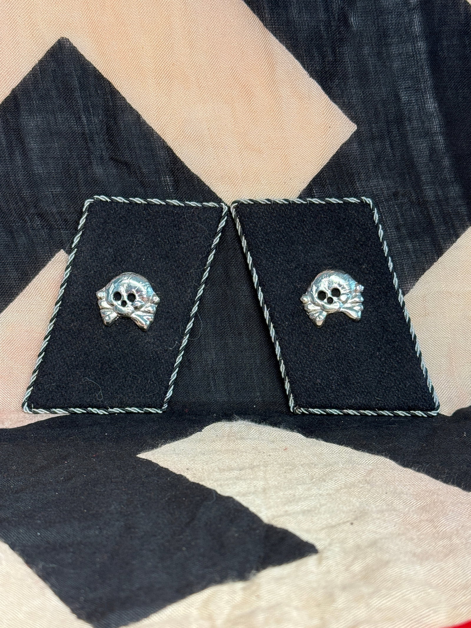 WW2 German Waffen SS Collar Tabs with Totenkopf Insignia: These black cloth collar tabs feature the Totenkopf (skull and crossbones) emblem, historically associated with certain SS units. Worn on the uniform collar, such insignia indicated unit affiliation o
