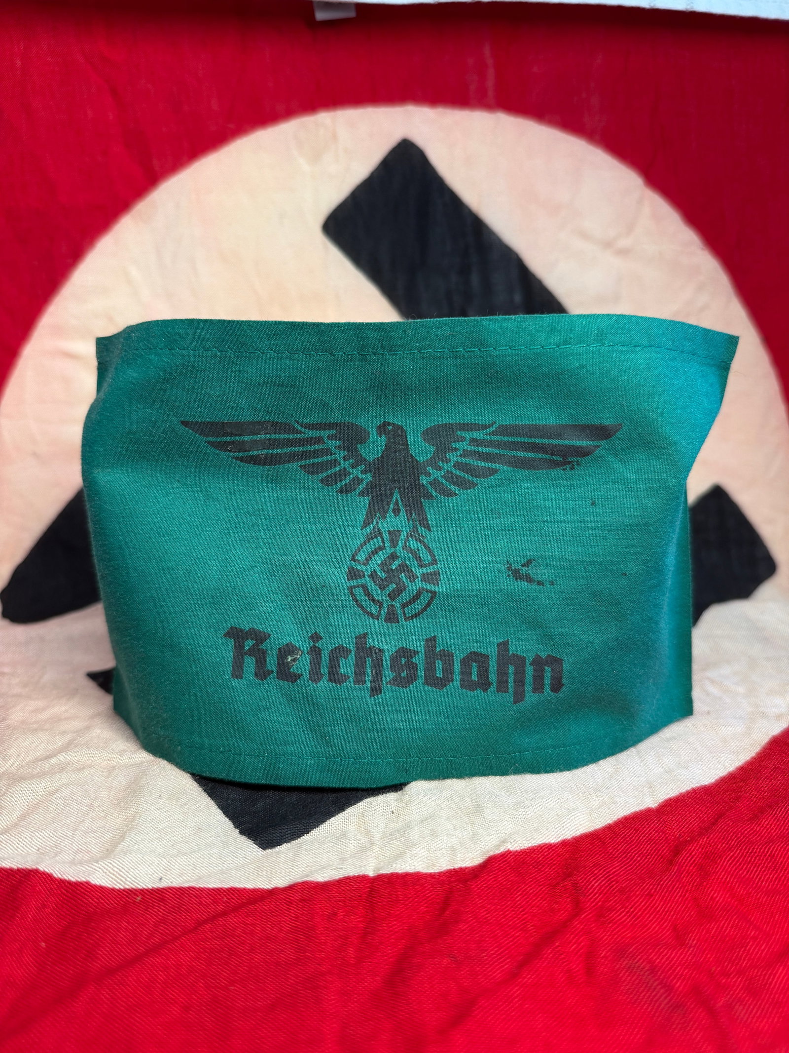 WW2 GERMAN Deutsche Reichsbahn Armband With RZM Paper Tag: This green cloth armband bears the inscription “Reichsbahn” beneath a stylized national eagle and emblem, identifying the wearer as affiliated with the Deutsche Reichsbahn, the state railway s