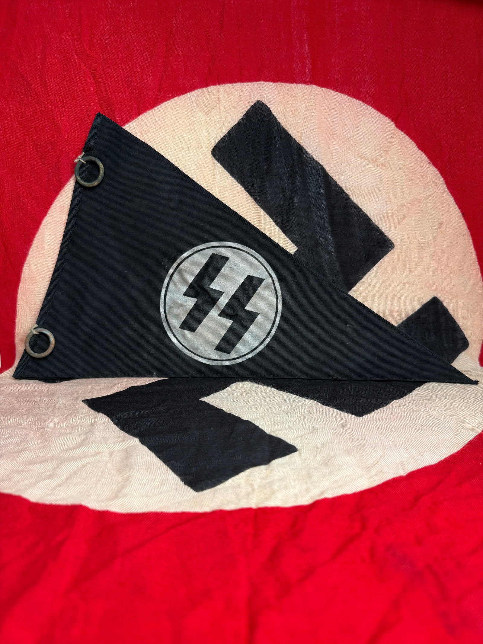 German WW2 SS Vehicle Pennant: This triangular vehicle pennant was used by members of the Schutzstaffel (SS) in Nazi Germany during the Second World War. Typically mounted on staff cars or official vehicles, such pennants served as