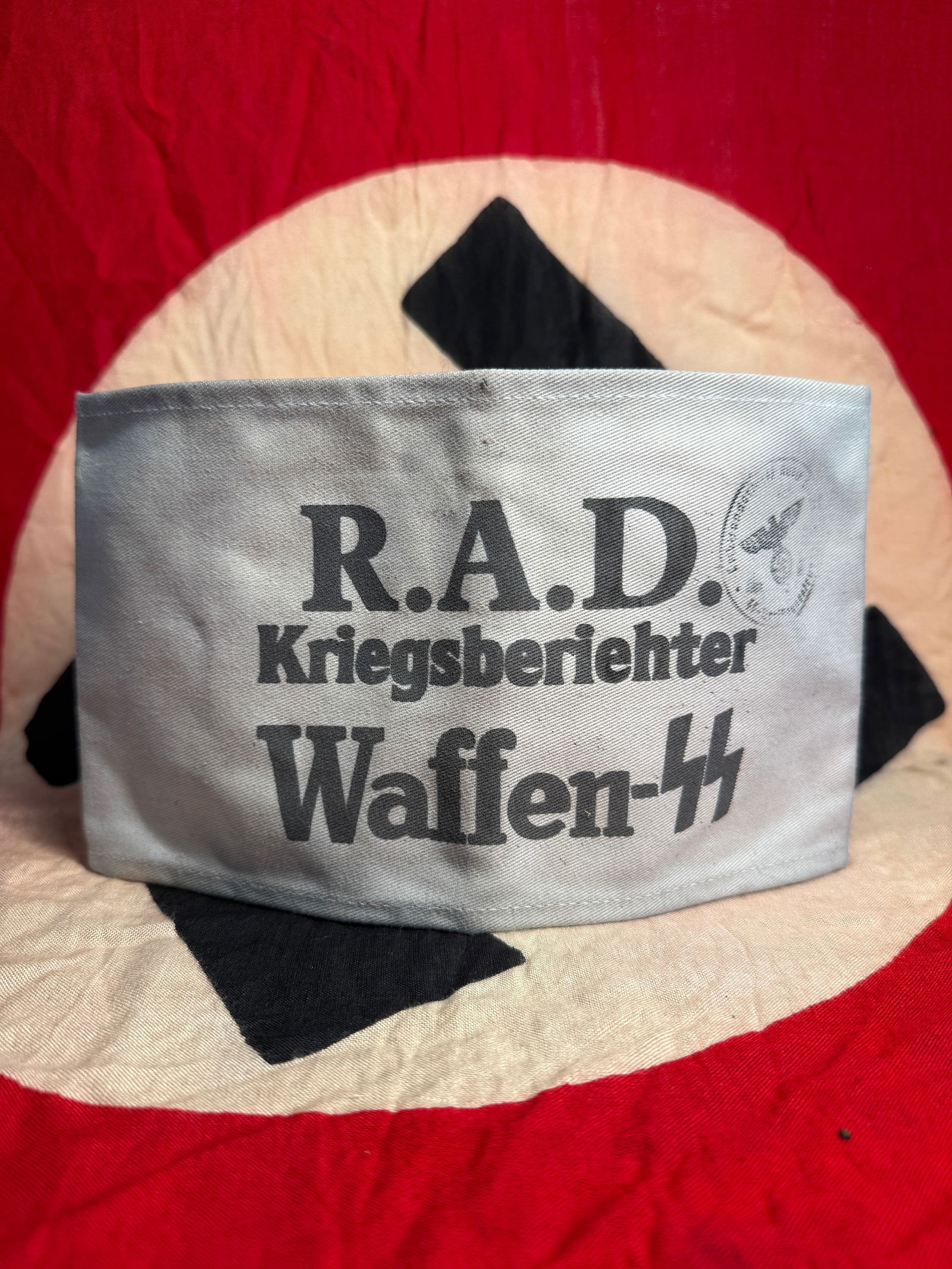 WW2 German Armband of a Waffen-SS War Correspondent (Kriegsberichter) With Inspection Stamp: This white cotton armband bears the printed inscription “R.A.D. Kriegsberichter Waffen-SS,” identifying the wearer as a war correspondent attached to Waffen-SS units. Such armbands were used t
