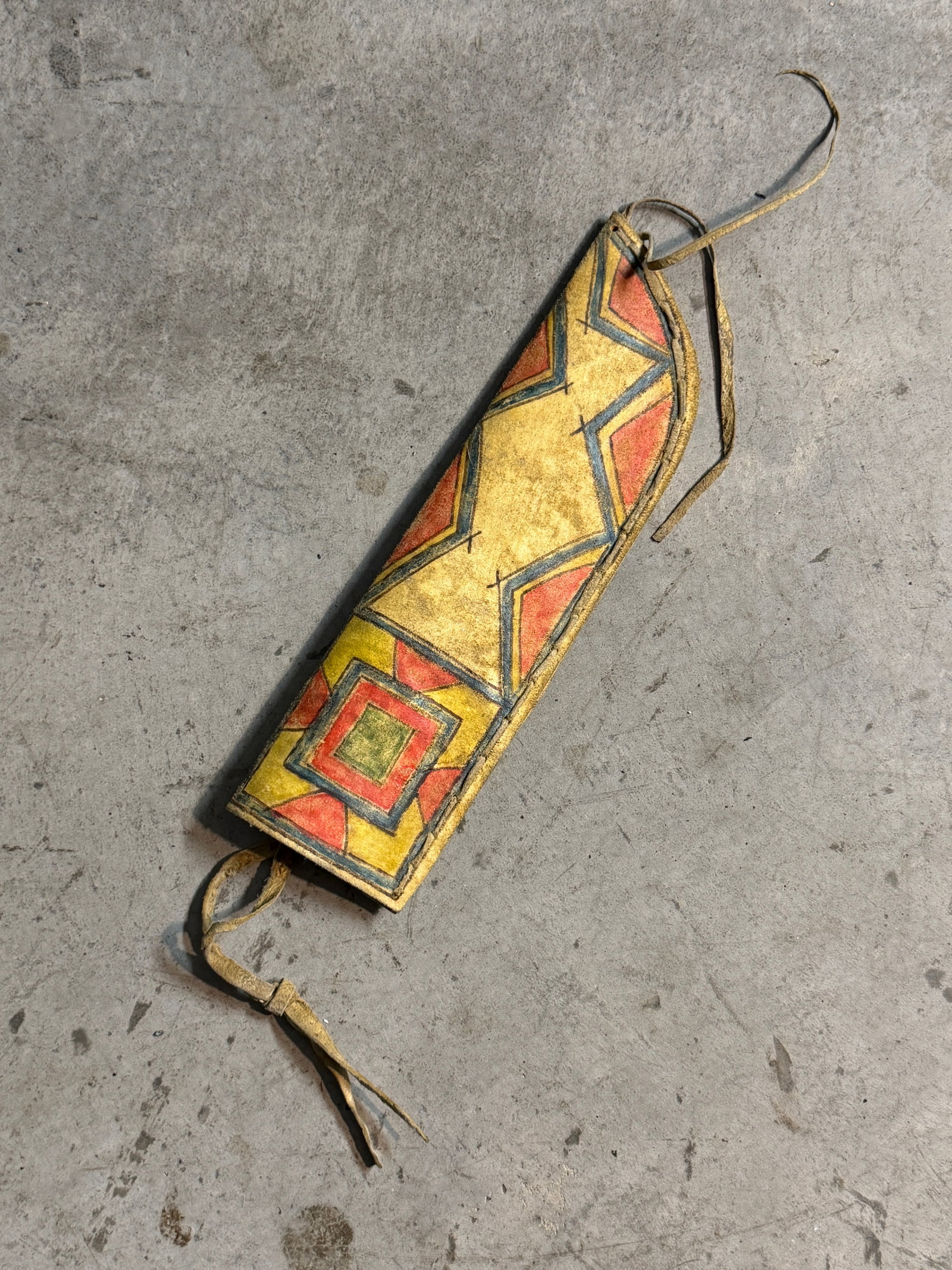 1800's Native American Hand Painted Rawhide Knife Sheath with Geometric Motifs, Plains Culture: This hand-painted rawhide sheath exemplifies the artistic and functional traditions of Plains Native American cultures. Formed from stiffened hide and stitched along the edges, the sheath was designed