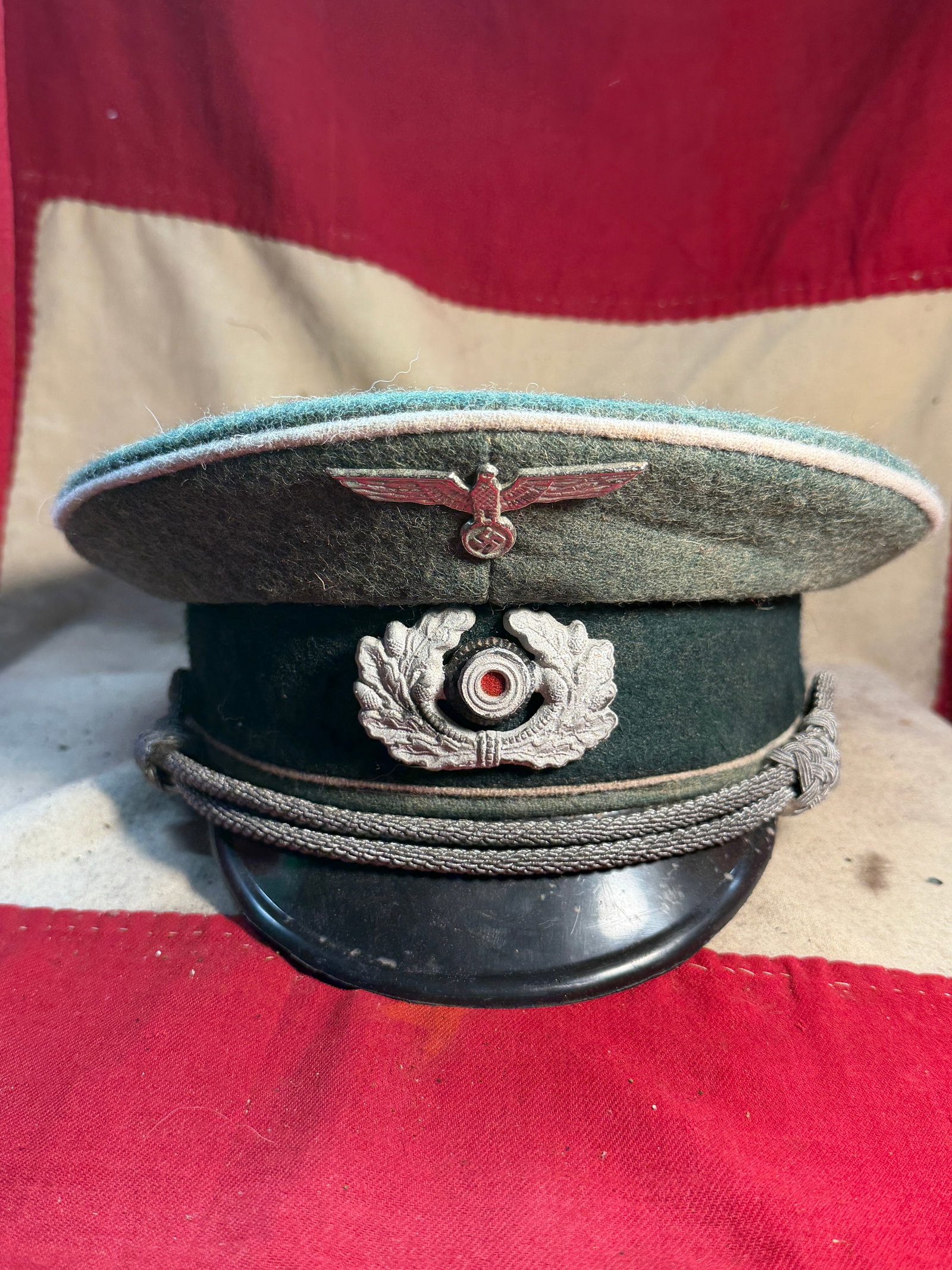 WW2 German Wehrmacht Army Officer’s Visor Cap (Schirmmütze), c. 1939–1945: This German Wehrmacht officer’s visor cap, known as a Schirmmütze, represents standard dress headgear worn by army officers during the Second World War. Constructed of field-gray wool with a dark g