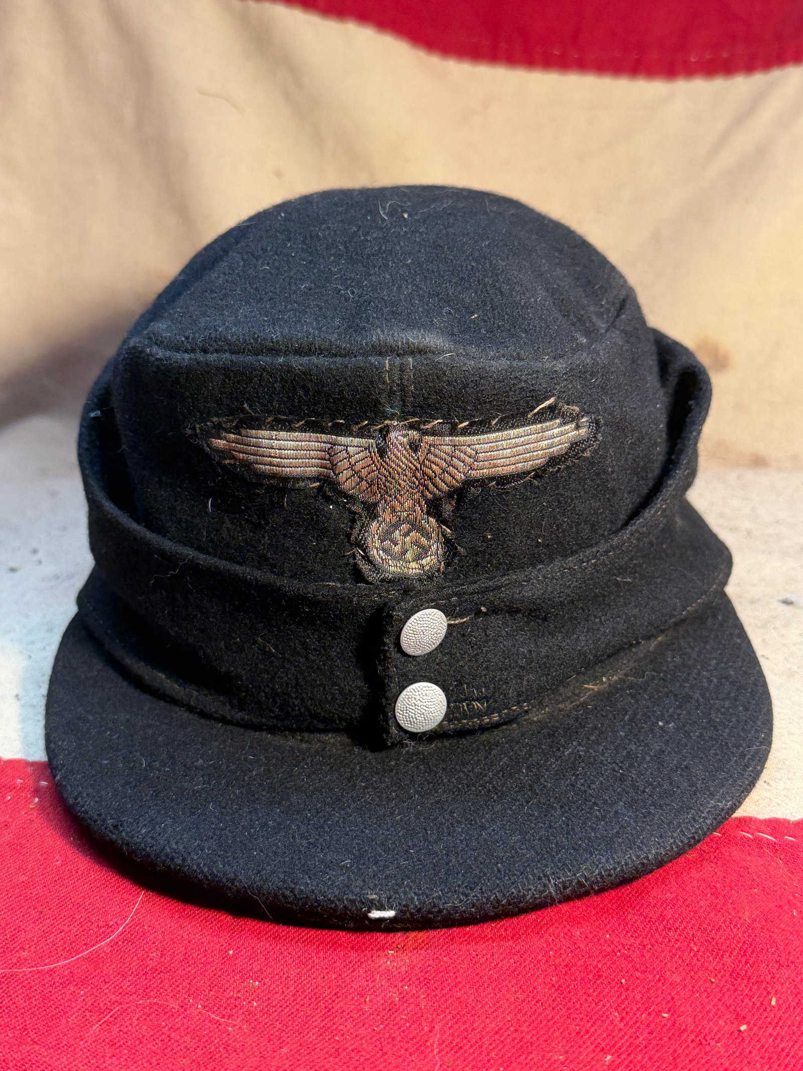 WW2 German Waffen-SS Field Cap (Arbeitsmütze), c. 1939–1945: This black wool field cap (Arbeitsmütze) is associated with the uniforms of the Waffen-SS during the Second World War. Designed for everyday wear, the cap features a soft, collapsible crown, a short