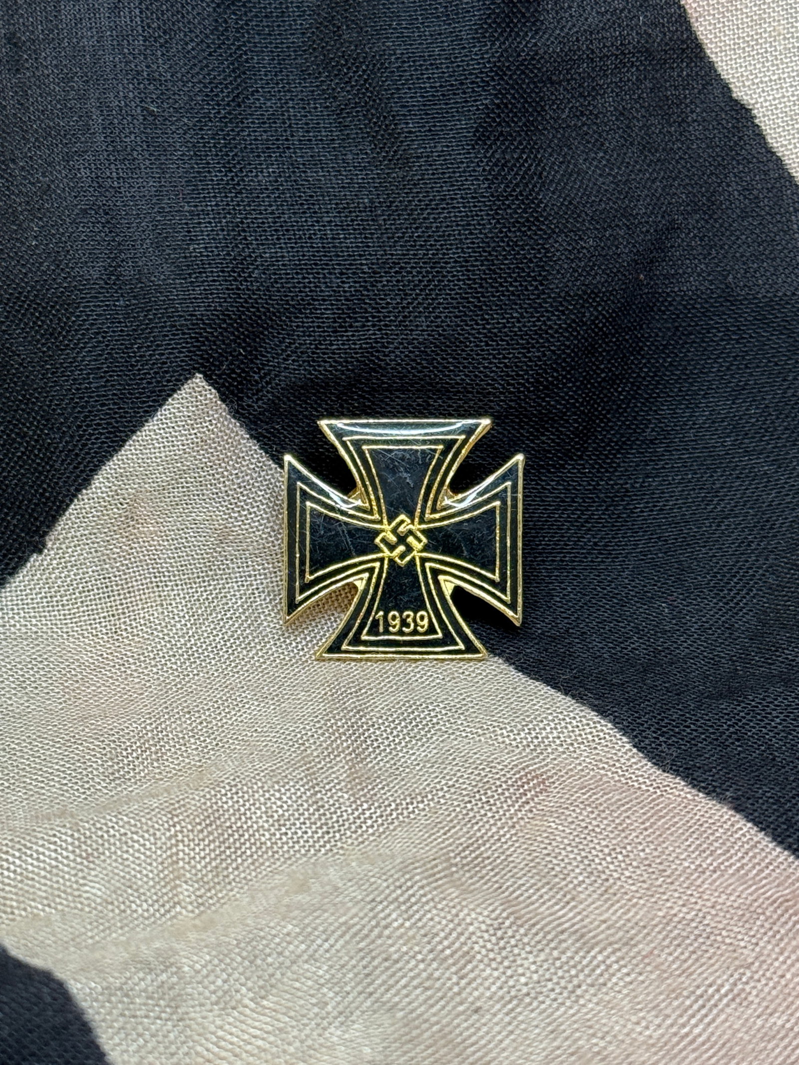 WWII German Iron Cross Lapel Pin (1939 Pattern): This enamel lapel pin represents a stylized version of the Iron Cross, one of Germany’s most recognizable military decorations, reissued in 1939 during the Second World War. The design features a bl