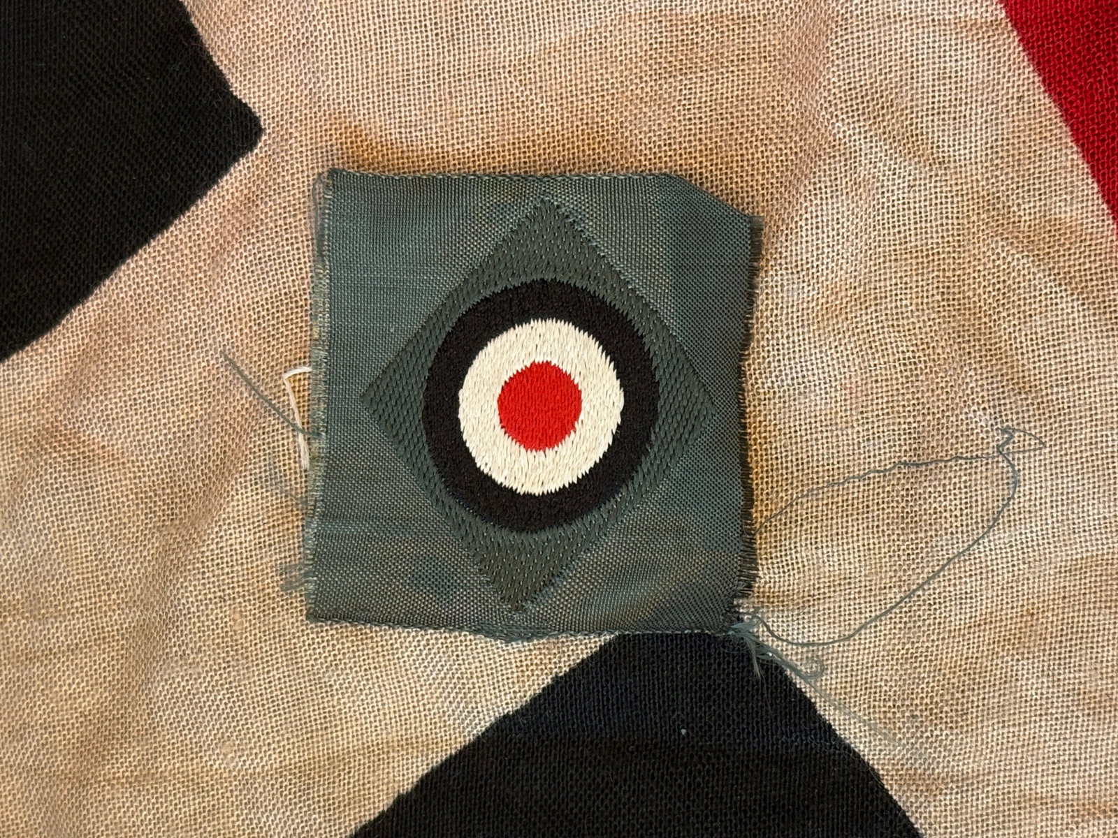 German National Cockade Patch – World War II Military Uniform Insignia: This embroidered cloth patch features the German national cockade, a circular emblem composed of concentric rings in black, white, and red. Mounted on a field-gray fabric backing, the design reflects