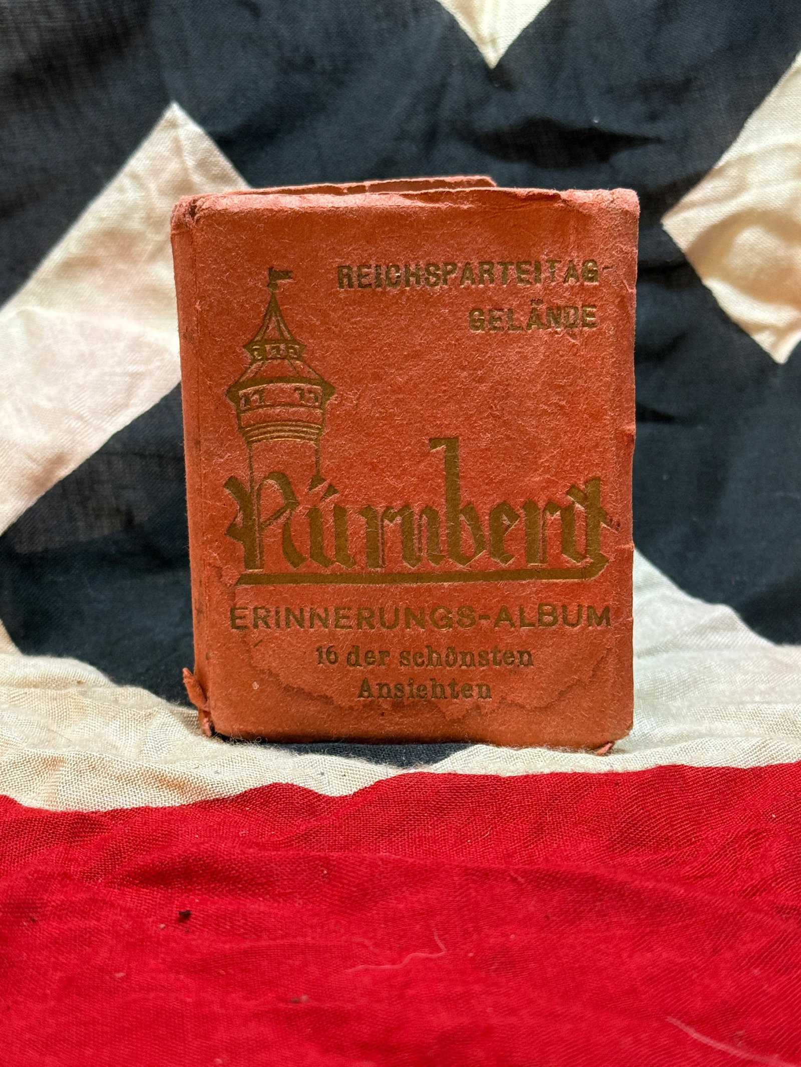 WWII Nuremberg Reichsparteitag Grounds Souvenir Album: This compact red-covered booklet, titled “Reichsparteitag Gelände Nürnberg – Erinnerungs-Album,” is a souvenir album produced for visitors to the Nazi Party Rally Grounds in Nuremberg. Con