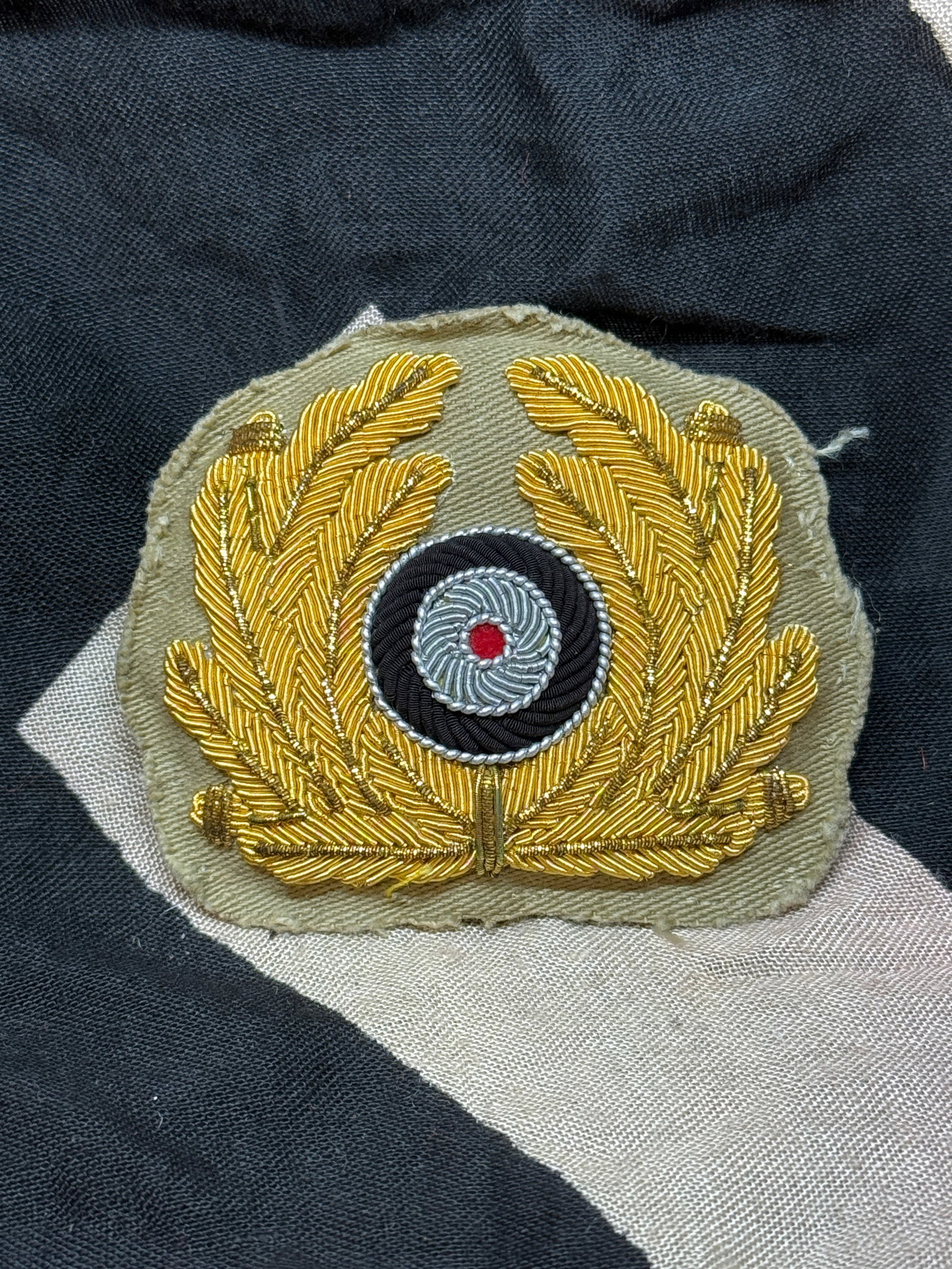 WWII German Kriegsmarine Officer’s Visor Cap Insignia: This finely crafted insignia consists of a gold bullion embroidered wreath of oak leaves surrounding a central cockade in black, white, and red—the national colors of Germany at the time. Worn on th