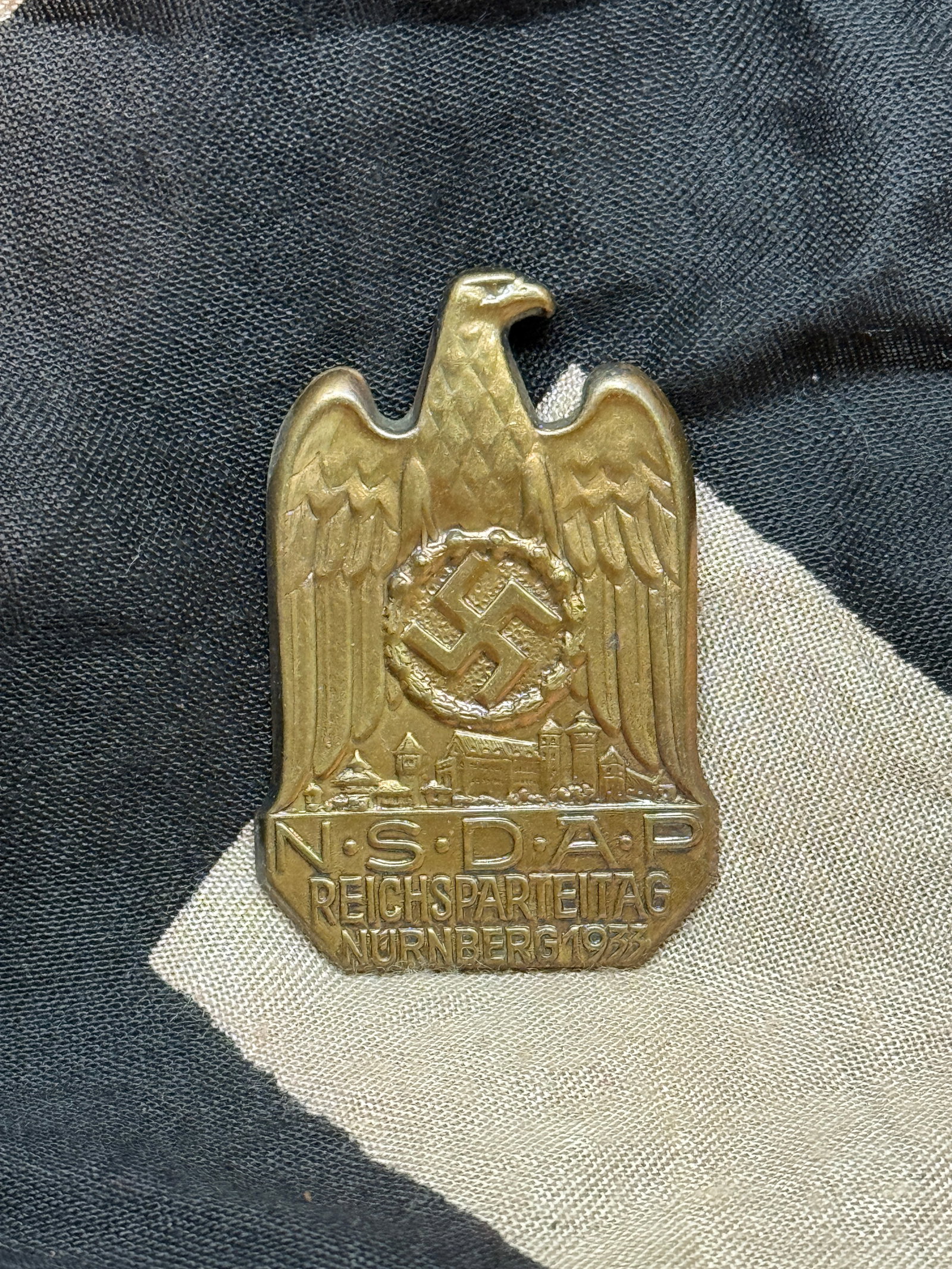 WWII German NSDAP Reichsparteitag Nürnberg 1933 Badge: This bronze-toned badge commemorates the 1933 Reichsparteitag (Nuremberg Rally), one of the earliest large-scale political rallies held by the National Socialist German Workers’ Party (NSDAP) follow