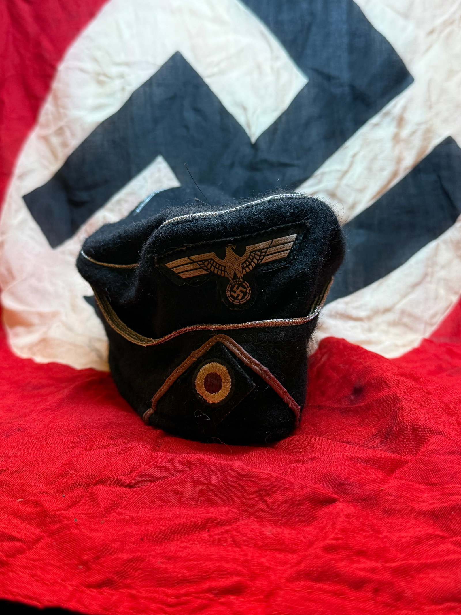 WWII German Waffen-SS / Political Visor Cap (Field Service Cap): This black wool field cap represents a style associated with Waffen-SS or political formations during the Second World War. The cap features a machine-applied national eagle insignia above a cockade, 