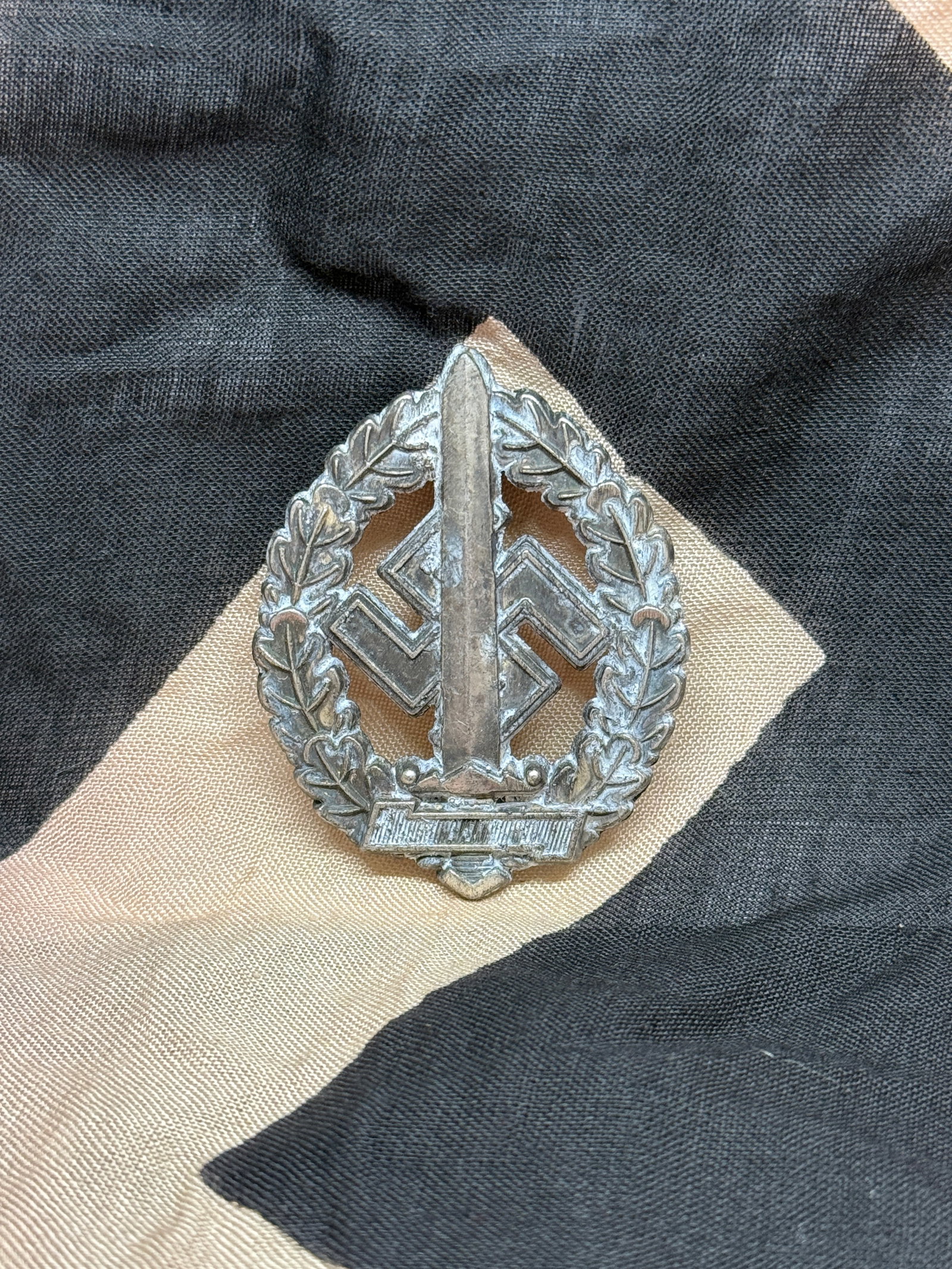 WWII German Infantry Assault Badge (Combat Qualification Award): This oval-shaped badge, featuring a central rifle over a swastika within an oak-leaf wreath, represents the German Infantry Assault Badge (Infanterie-Sturmabzeichen). Awarded to infantry soldiers who