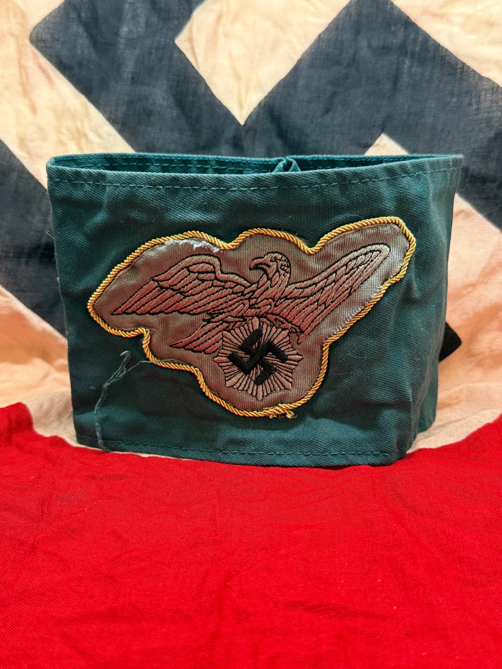 WWII German RAD (Reichsarbeitsdienst) Armband with National Eagle Insignia: This cloth armband is associated with the Reichsarbeitsdienst (RAD), the state labor service organization in Nazi Germany during World War II. Constructed from dark green fabric, the armband features