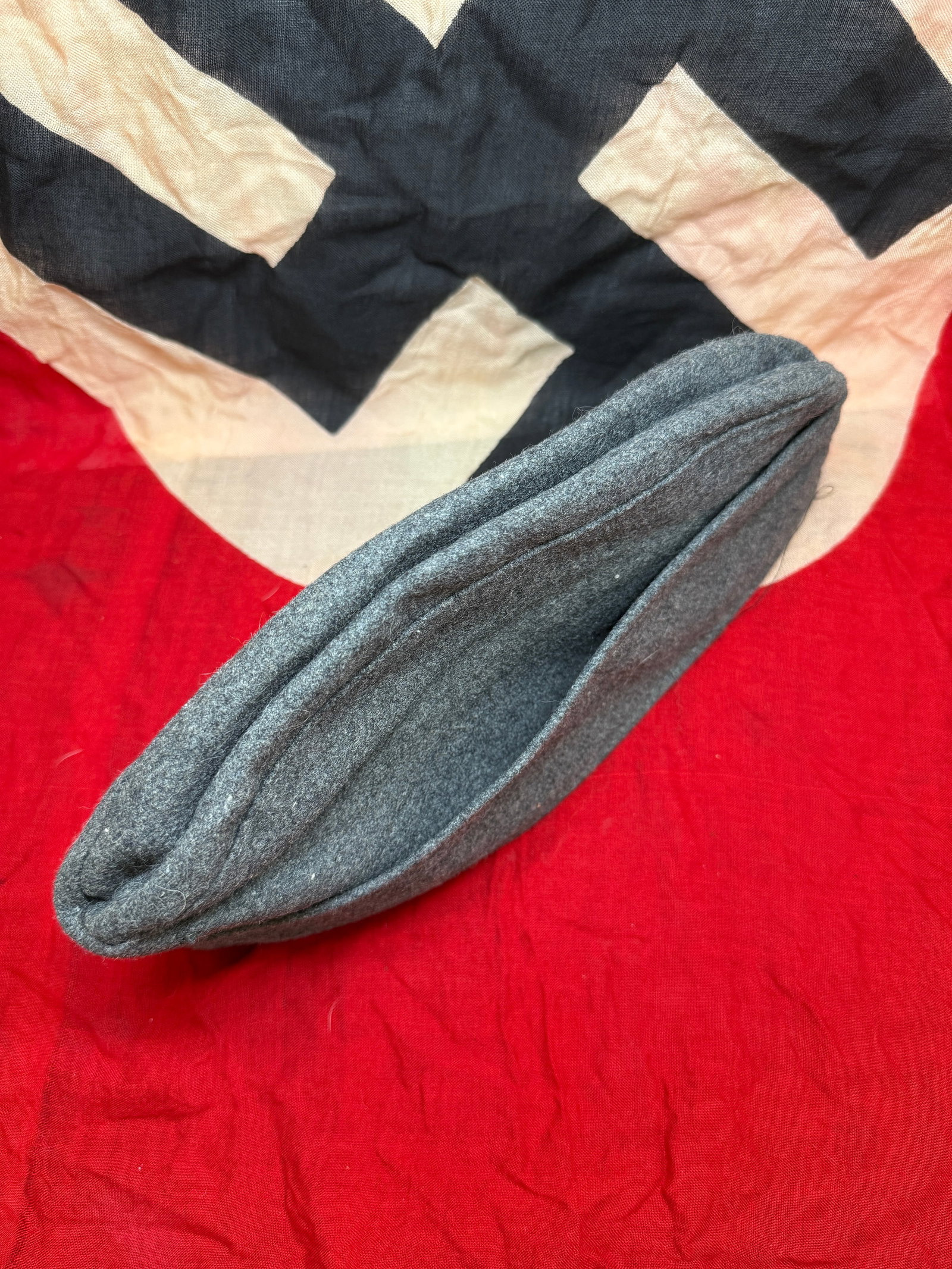 WWII German Luftwaffe M43 Field Cap (Einheitsfeldmütze) with Eagle Insignia: World War II-era German Luftwaffe M43 field cap (Einheitsfeldmütze) is constructed from blue-grey wool, characteristic of Luftwaffe uniform materials. The cap features the standard fold-down side pan