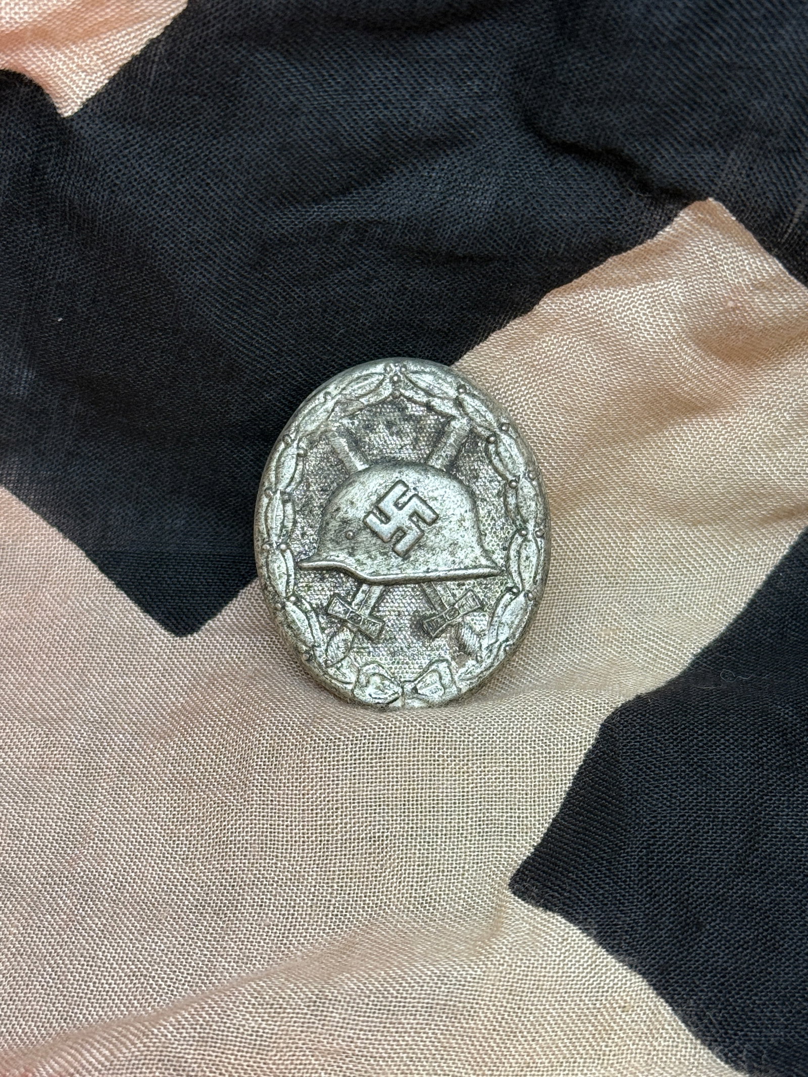 WWII German Wound Badge in Silver (Verwundetenabzeichen in Silber): World War II German Wound Badge in Silver (Verwundetenabzeichen in Silber), awarded to military personnel wounded multiple times in combat or for a single severe injury. The badge features a steel hel