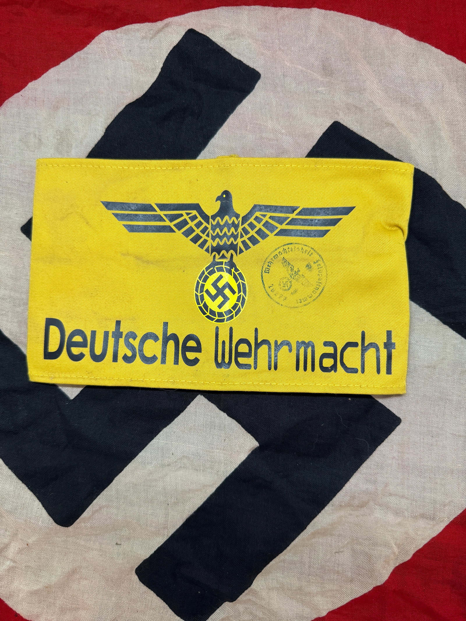 WWII German Wehrmacht Armband (Deutsche Wehrmacht Printed Variant): A yellow cotton armband printed with a stylized eagle clutching a swastika above the words “Deutsche Wehrmacht.” This type of armband was typically used for identification purposes, possibly b