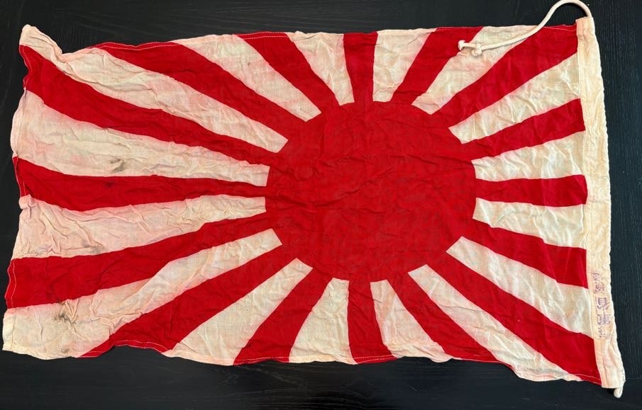 WWII Imperial Japanese Rising Sun Flag: This flag displays a central red disc with radiating red rays extending outward across a white field, commonly known as the Rising Sun design. During World War II, this pattern was used by the Imperia