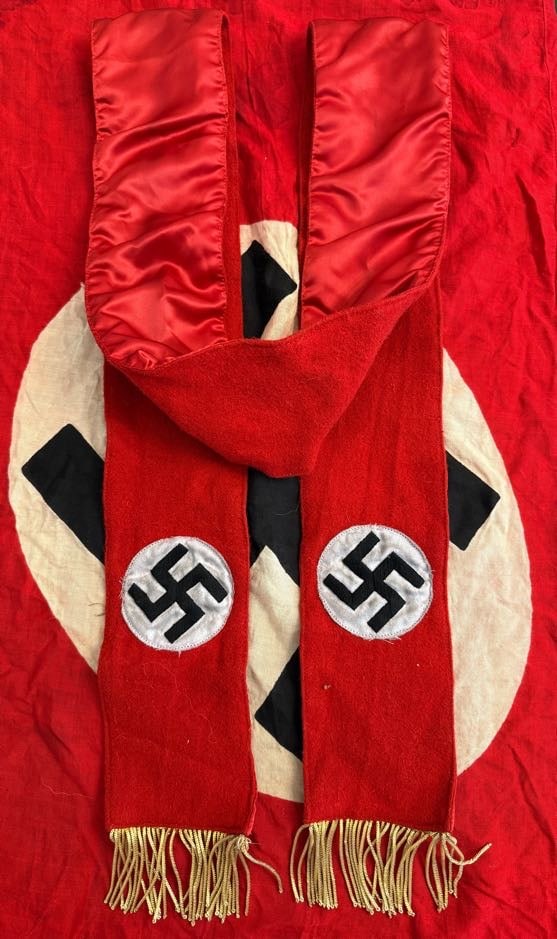 WWII German NSDAP/SS Ceremonial Funeral Sash with Double Swastika Roundels: This red wool ceremonial sash displays two white roundels with black swastikas, each positioned symmetrically along its length, and is finished with gold fringe. The satin-lined interior and reinforce