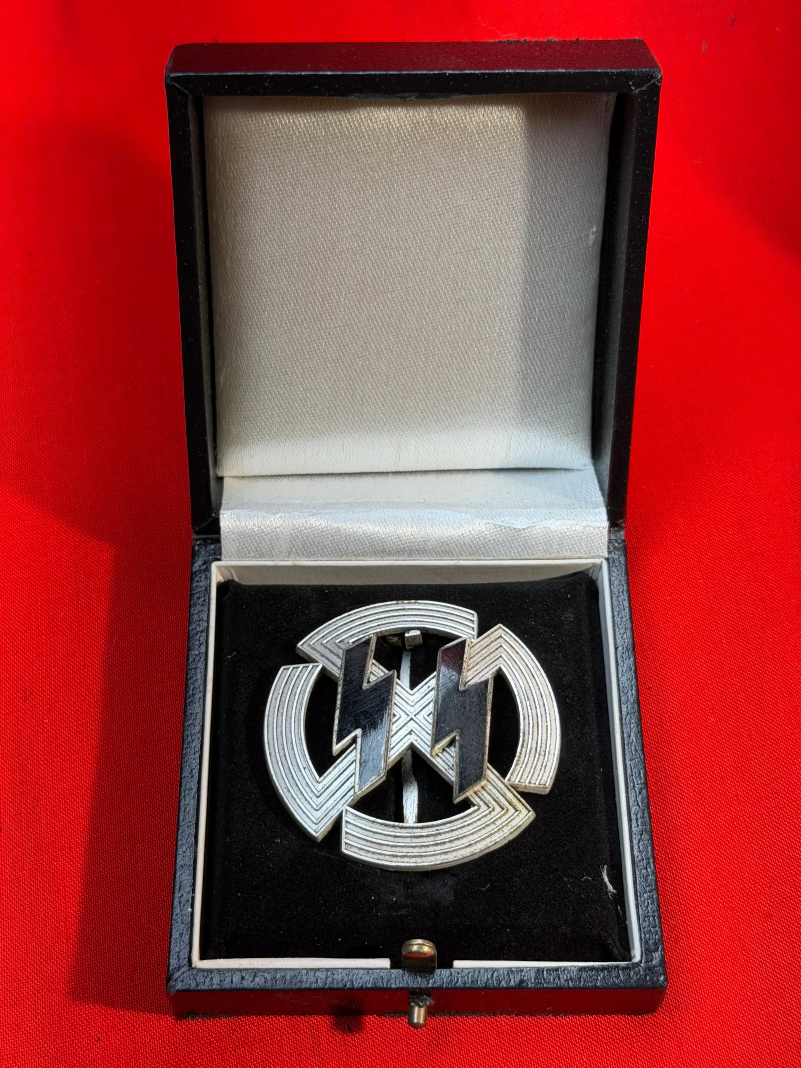 Cased WW2 German SS Membership Badge (Schutzstaffel), Nazi Germany, c. 1930s–1940s By RZM: This metal badge features the stylized twin lightning-bolt “SS” runes, the emblem of the Schutzstaffel (SS), a paramilitary organization of the Nazi regime. The design incorporates geometric c