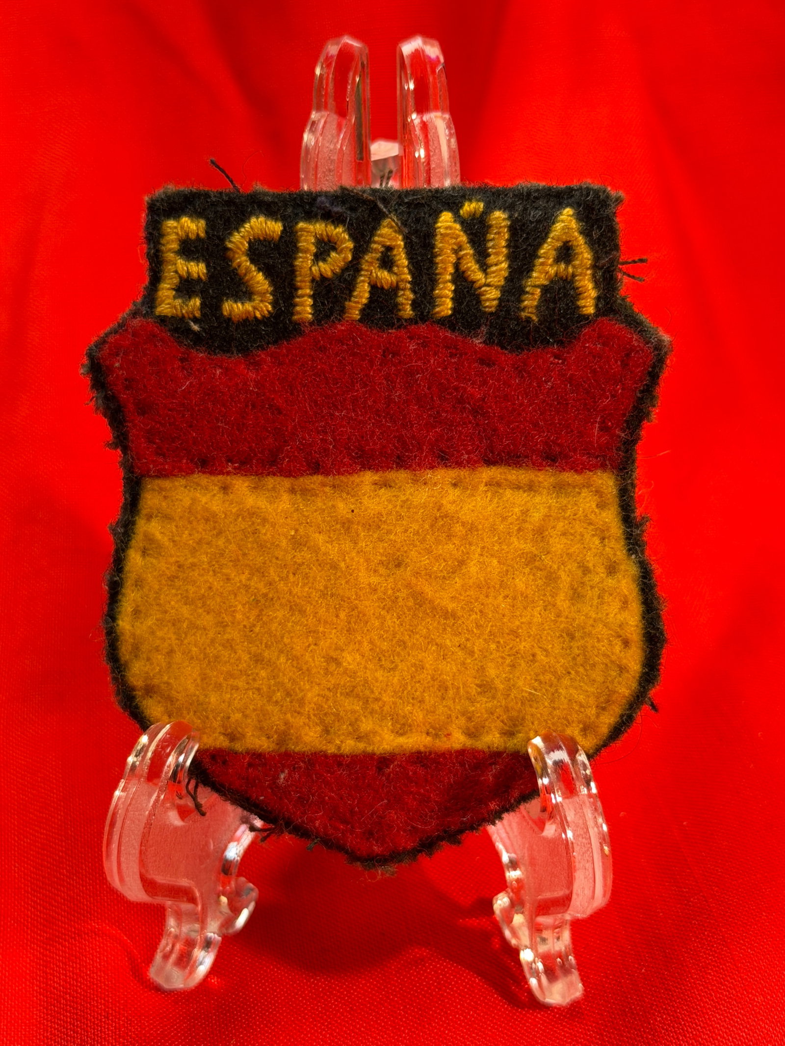 WW2 Spanish Volunteer “ESPAÑA?? Shield Sleeve Patch – Spanish Division Style Insignia: A wool construction shield-style sleeve patch featuring the word “ESPAÑA” embroidered in yellow thread across a black upper field, with a red and yellow horizontal color scheme below represen