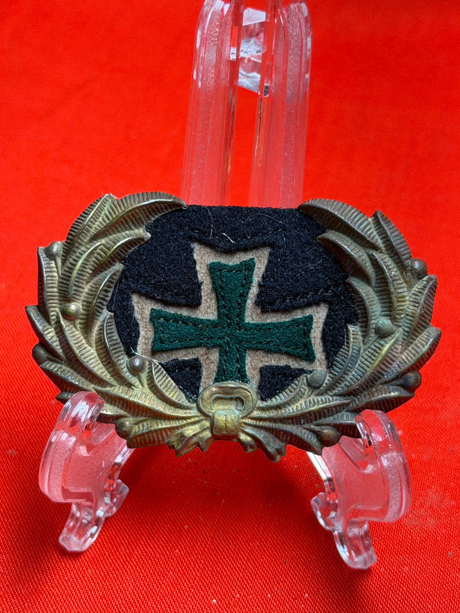 Civil War Hospital Corps Steward’s Headgear Badge with Maltese Cross: This headgear badge features a Maltese-style cross design set against a dark cloth backing, framed by an ornate wreath with detailed leaf elements. The cross is rendered in green with a lighter border