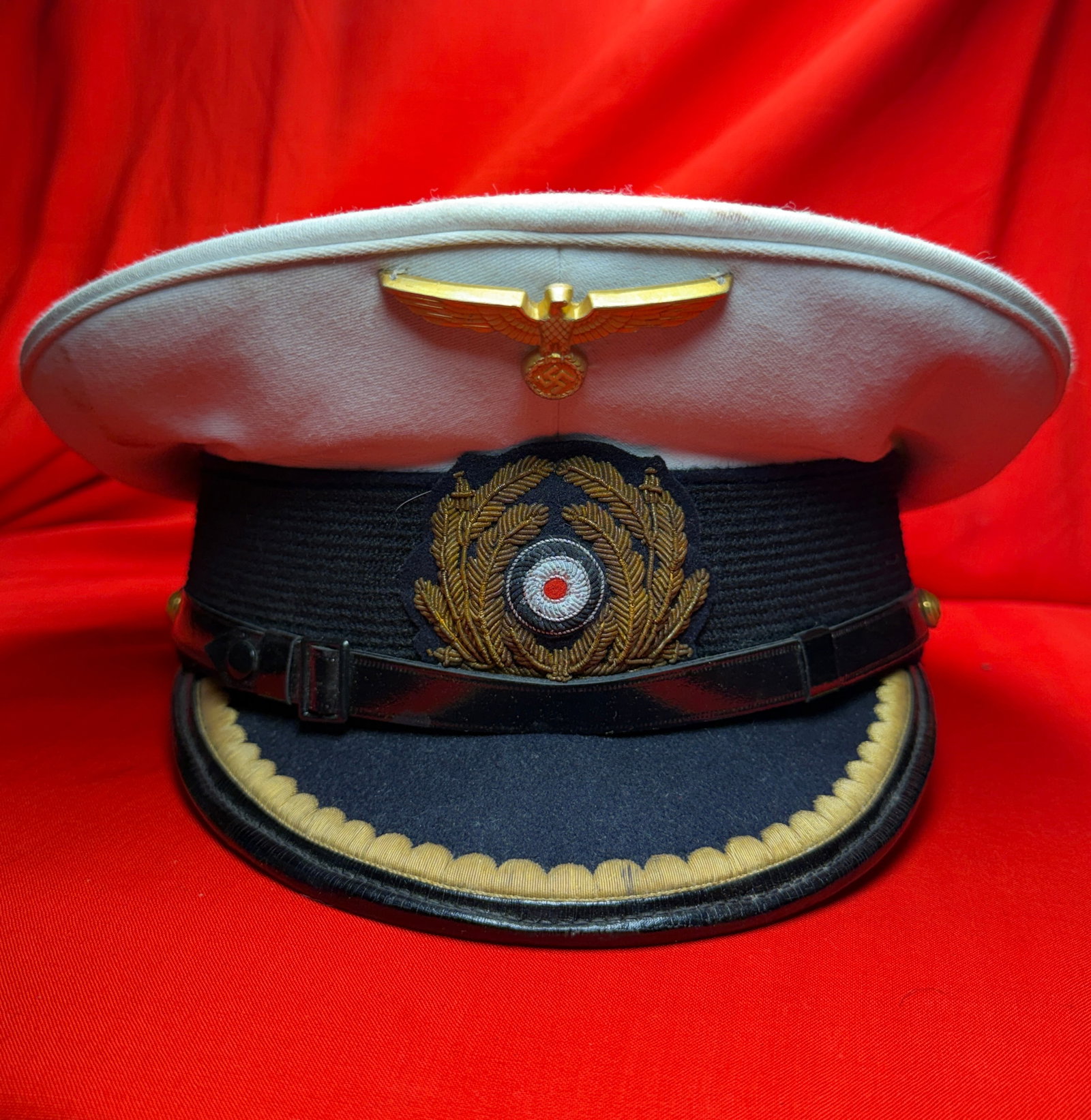 WW2 German Kriegsmarine U-Boat Junior Officer Style Visor Cap White Top Navy Cap By Deutsche Arbeit: This visor cap features a classic naval-style design with a white top crown, dark band, and black visor, reflecting a traditional officer presentation. The front is detailed with a metal eagle insigni