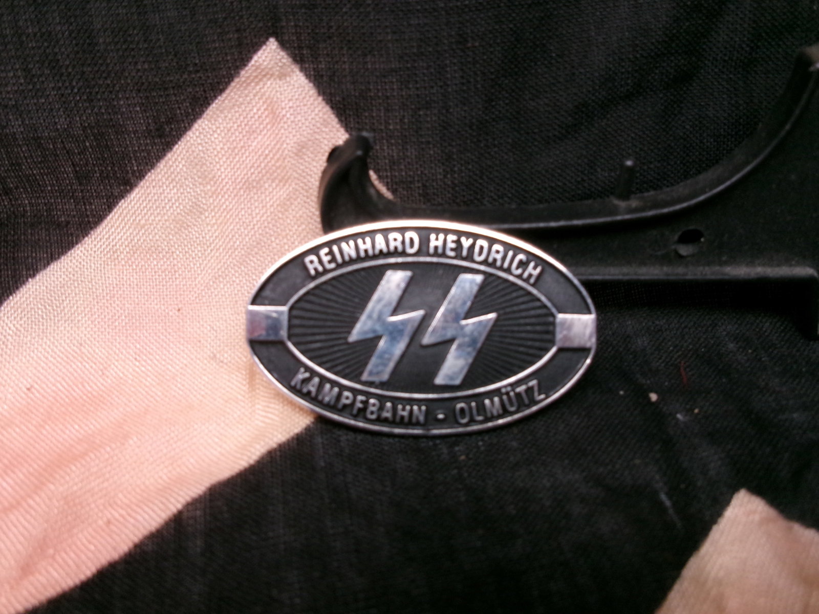 WWII German SS "Reinhard Heydrich" Commemorative Badge (Kampfbahn Olmütz): This oval metal badge bears the name “Reinhard Heydrich” along with SS runes and the inscription “Kampfbahn – Olmütz” (Olomouc). Such badges were associated with memorial events, at