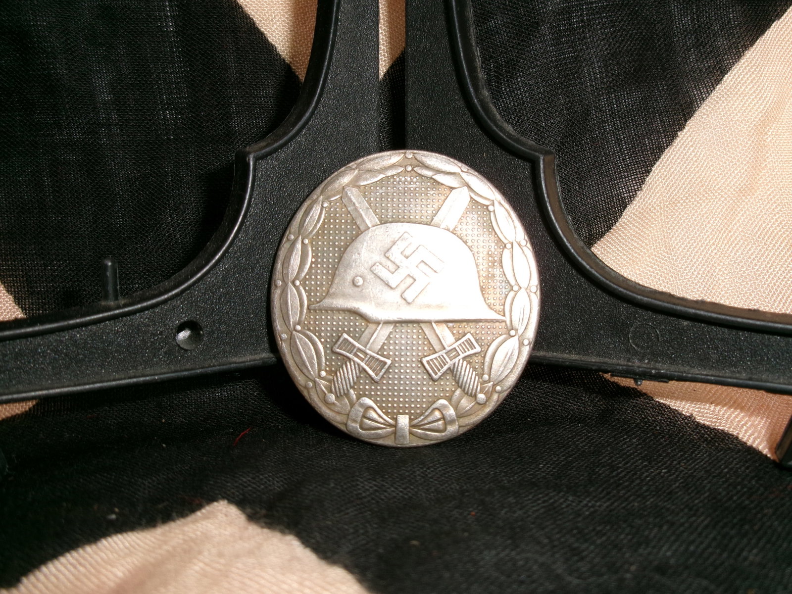 WWII German Wound Badge in Silver (Verwundetenabzeichen): This circular metal badge, featuring a steel helmet with a swastika above crossed swords and surrounded by a laurel wreath, is the Wound Badge in Silver, awarded to German soldiers wounded multiple ti