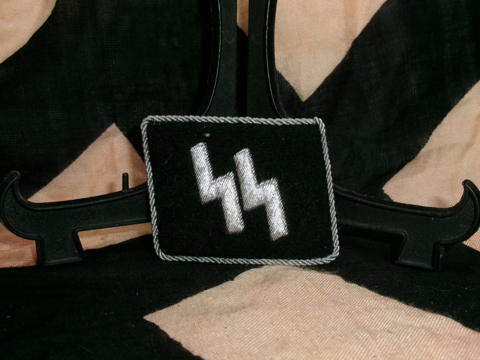 WWII Waffen-SS Collar Tab (Runic “SS?? Insignia): This black cloth collar tab features the distinctive silver embroidered double “Sig rune,” the emblem of the Waffen-SS, Nazi Germany’s elite paramilitary force during World War II. Worn on t