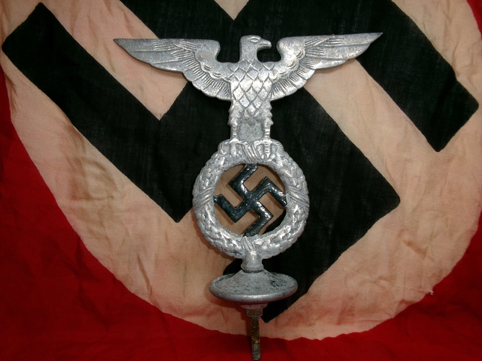 WWII German Eagle-and-Wreath Finial (Flagpole or Standard Top Ornament): This metal object depicts a spread-wing eagle perched above a wreath encircling a swastika, mounted on a threaded base for attachment. The form strongly resembles finials used atop flagpoles, standard