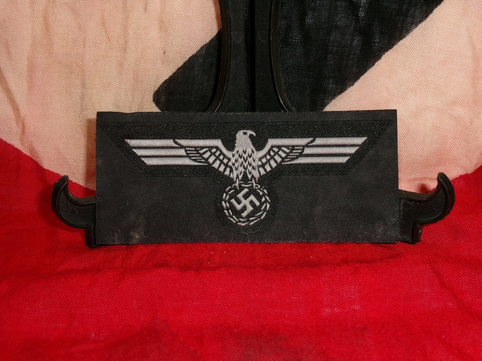 WWII German Waffen-SS Eagle Cloth Sleeve Insignia: This cloth sleeve insignia features the stylized eagle with outstretched wings above a wreath design, commonly associated with Waffen-SS uniforms during the World War II era. The emblem is printed in 