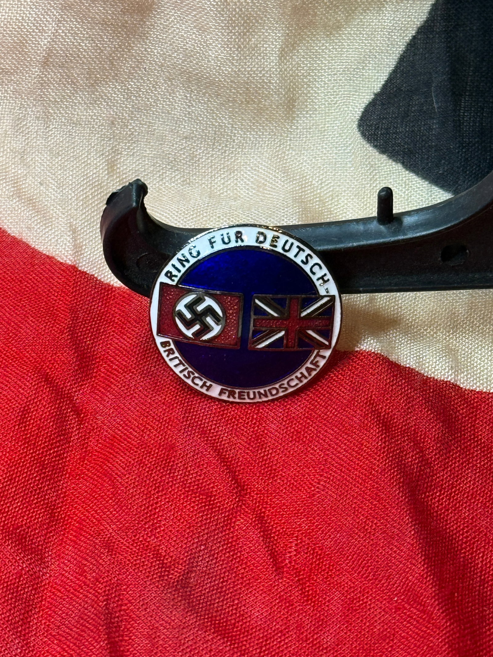 WWII German–British Friendship Enamel Badge (“Ring für Deutsch-Britisch Freundschaft??): This circular enamel badge features a blue center with crossed flags, including a German flag with swastika and the British Union Jack, surrounded by the inscription “Ring für Deutsch-Britisch Freu