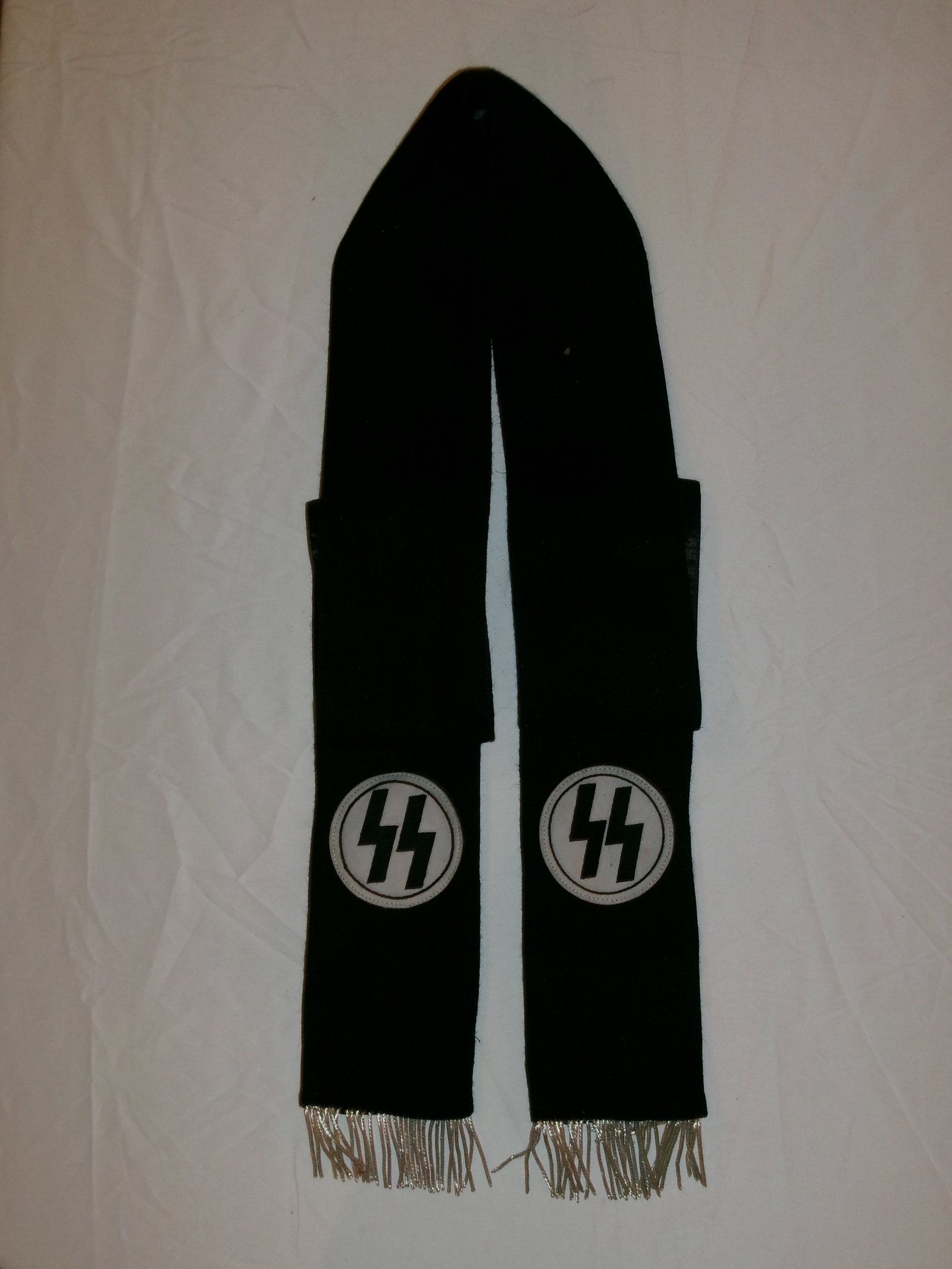WWII German Waffen-SS Ceremonial Scarf (Black with SS Runes Roundels): This black scarf features two circular white disks each containing the SS “Sig” runes in black, positioned symmetrically near the ends. The scarf is finished with light-colored fringe, suggest