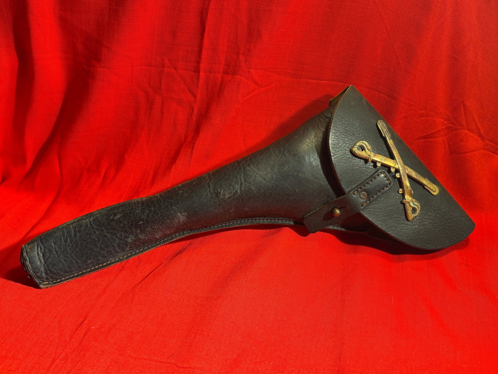 Civil War Style Cavalry Dragoon Leather Holster with Crossed Swords Emblem: Black leather cavalry dragoon holster featuring a long tapered body and full protective flap with strap and stud closure. The front is fitted with a crossed swords metal emblem, giving it a distinctiv