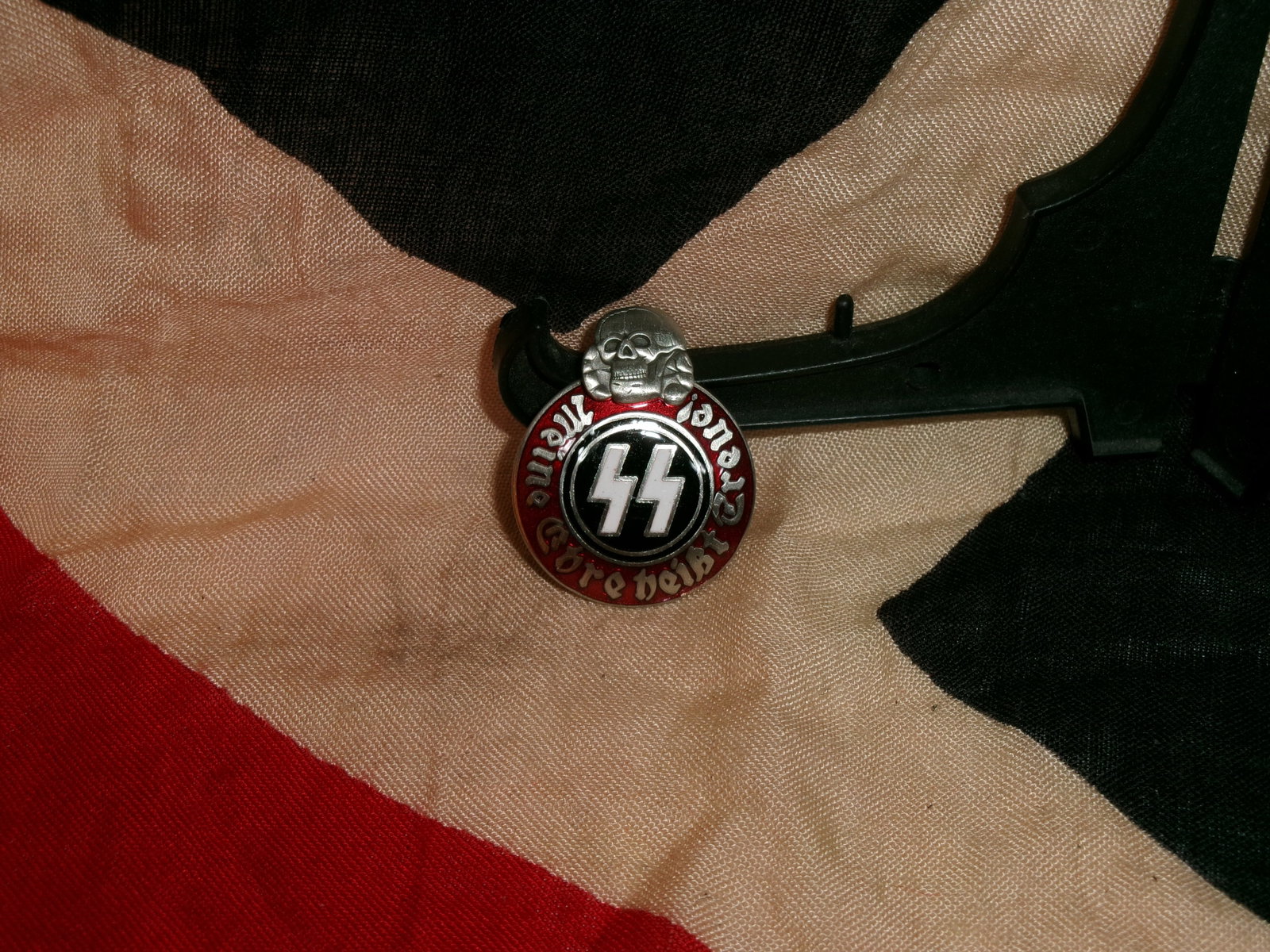 WWII Waffen-SS Membership Badge (“Meine Ehre heißt Treue??) By Ges. Gesch. RZM M13/42 SS: A circular enamel membership badge associated with the Waffen-SS, featuring the SS runes beneath a Totenkopf (skull) and encircled by the motto “Meine Ehre heißt Treue” (“My honor is loyalt