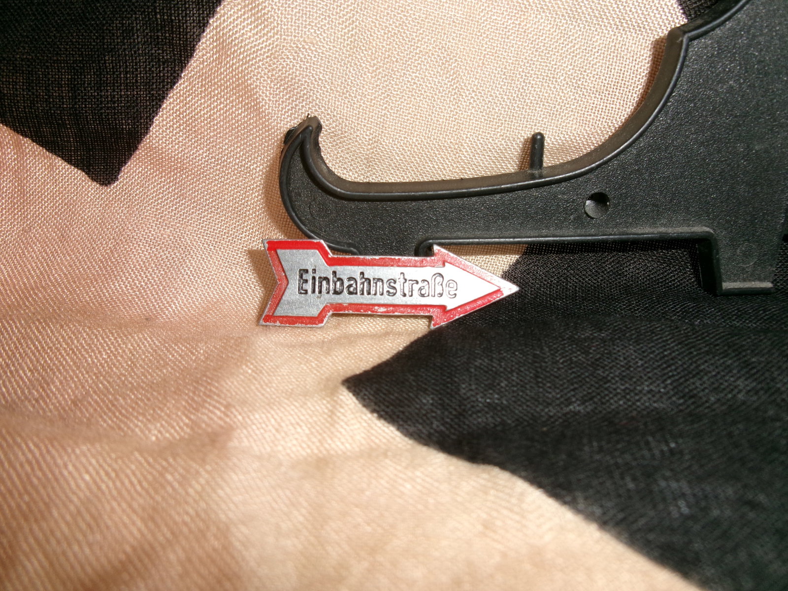 WWII German “Einbahnstraße?? Directional Novelty Badge (One-Way Street Tinnie): A small enameled metal badge in the form of a directional arrow bearing the German word “Einbahnstraße” (“One-Way Street”). Such novelty or slogan badges were commonly produced in the