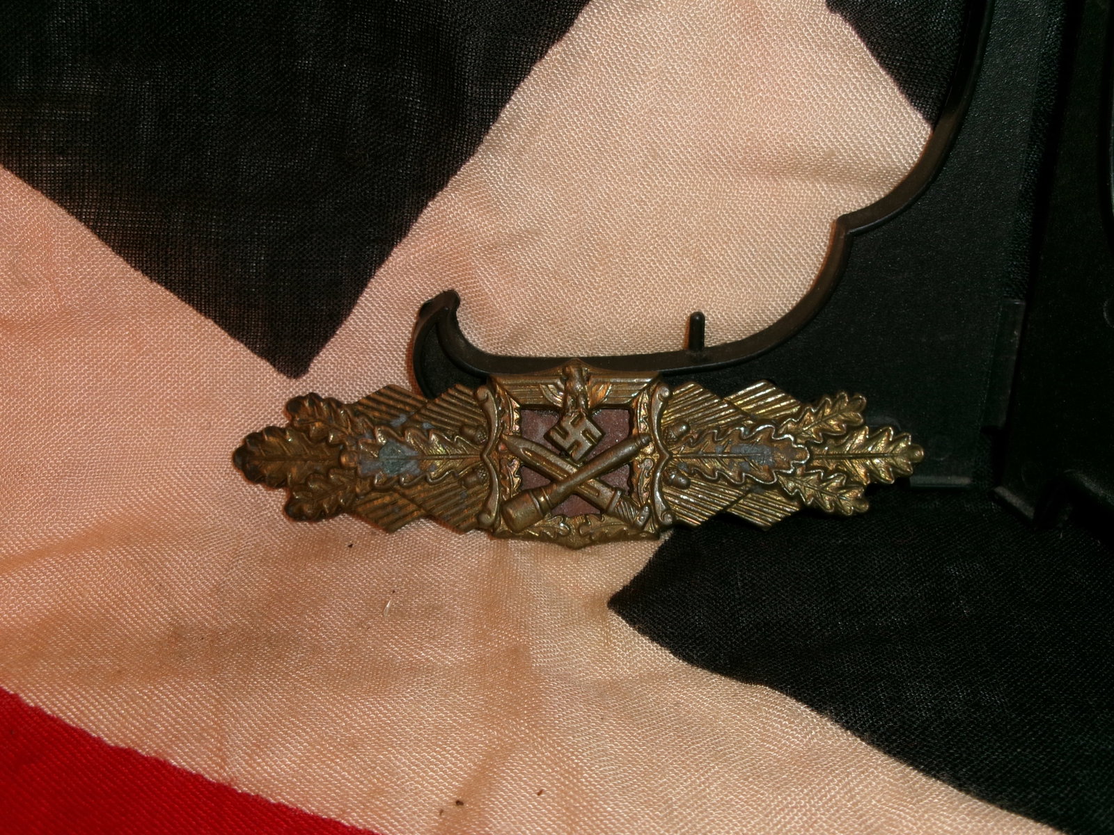 WWII German Close Combat Clasp (Nahkampfspange), Bronze Grade - Maker Marked: This metal award depicts crossed weapons over a central swastika, framed by oak leaves and an eagle. Issued to German soldiers who engaged in repeated close-quarters combat, the clasp recognized susta