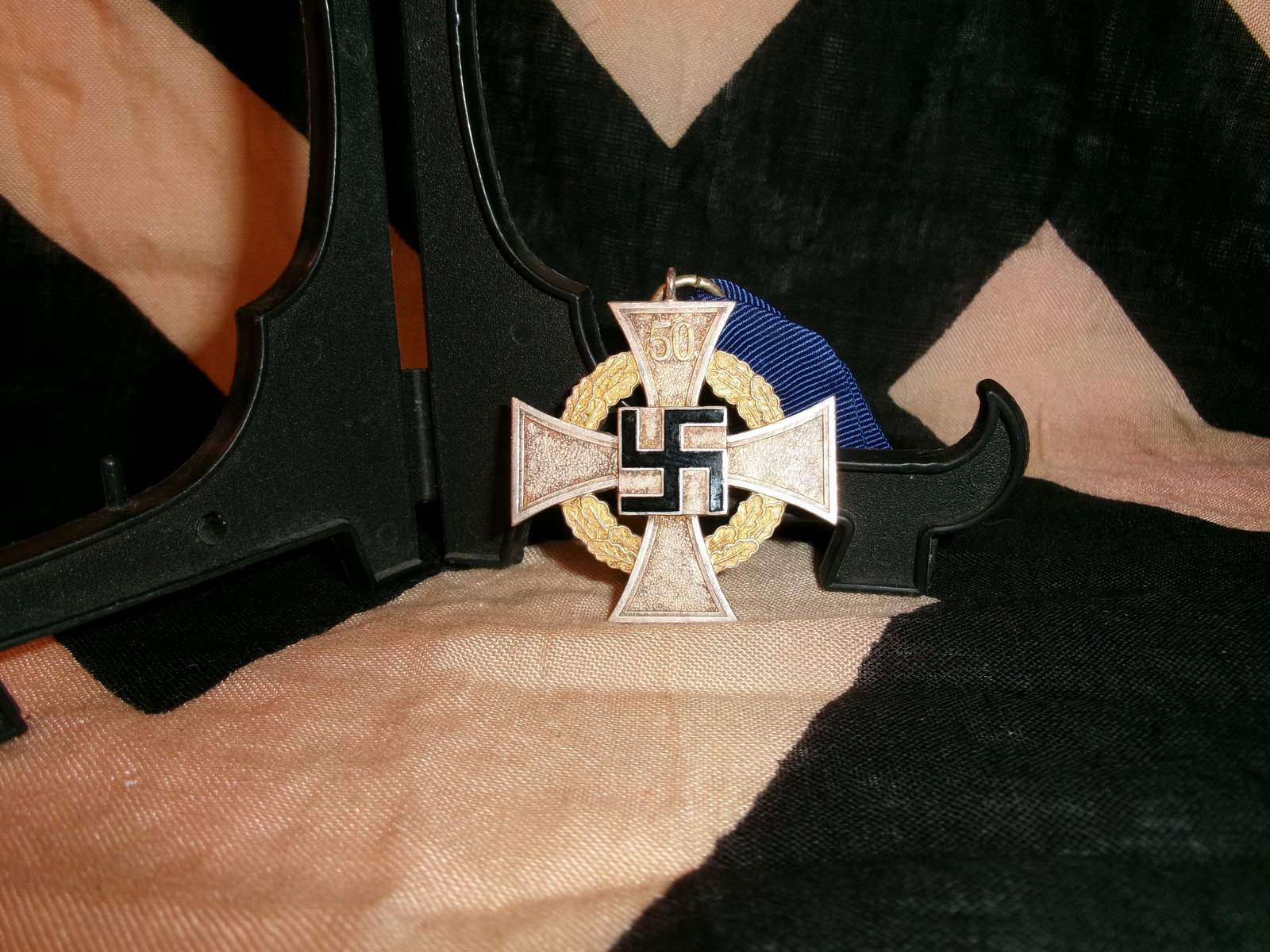 WWII German Faithful Service Cross, 50-Year Civil Service Award (Treudienst-Ehrenzeichen): This medal represents the 50-year class of the Faithful Service Cross, awarded to long-serving civil servants. The decoration features a white enameled cross with a central emblem, backed by a gilt oa