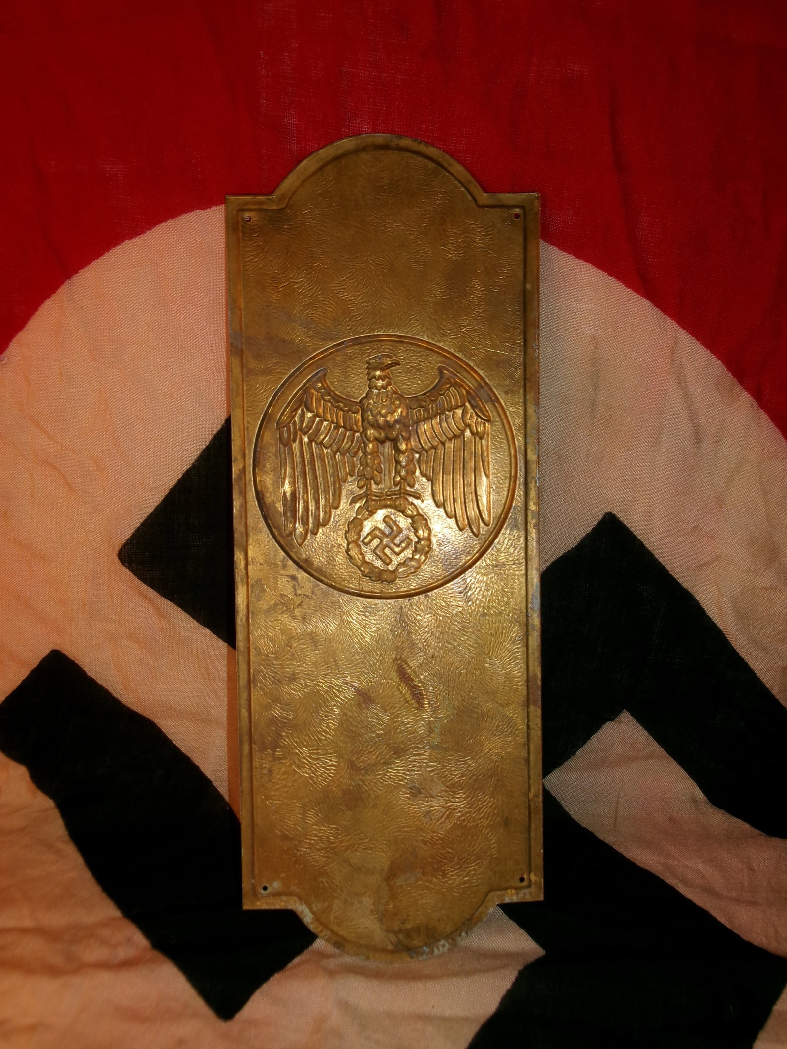 WWII German Reich Eagle Door Push Plate or Decorative Plaque: This rectangular metal plate features a raised eagle above a wreath, rendered in a bronze-toned finish against a textured background. Mounting holes at the corners indicate it was designed for attachm