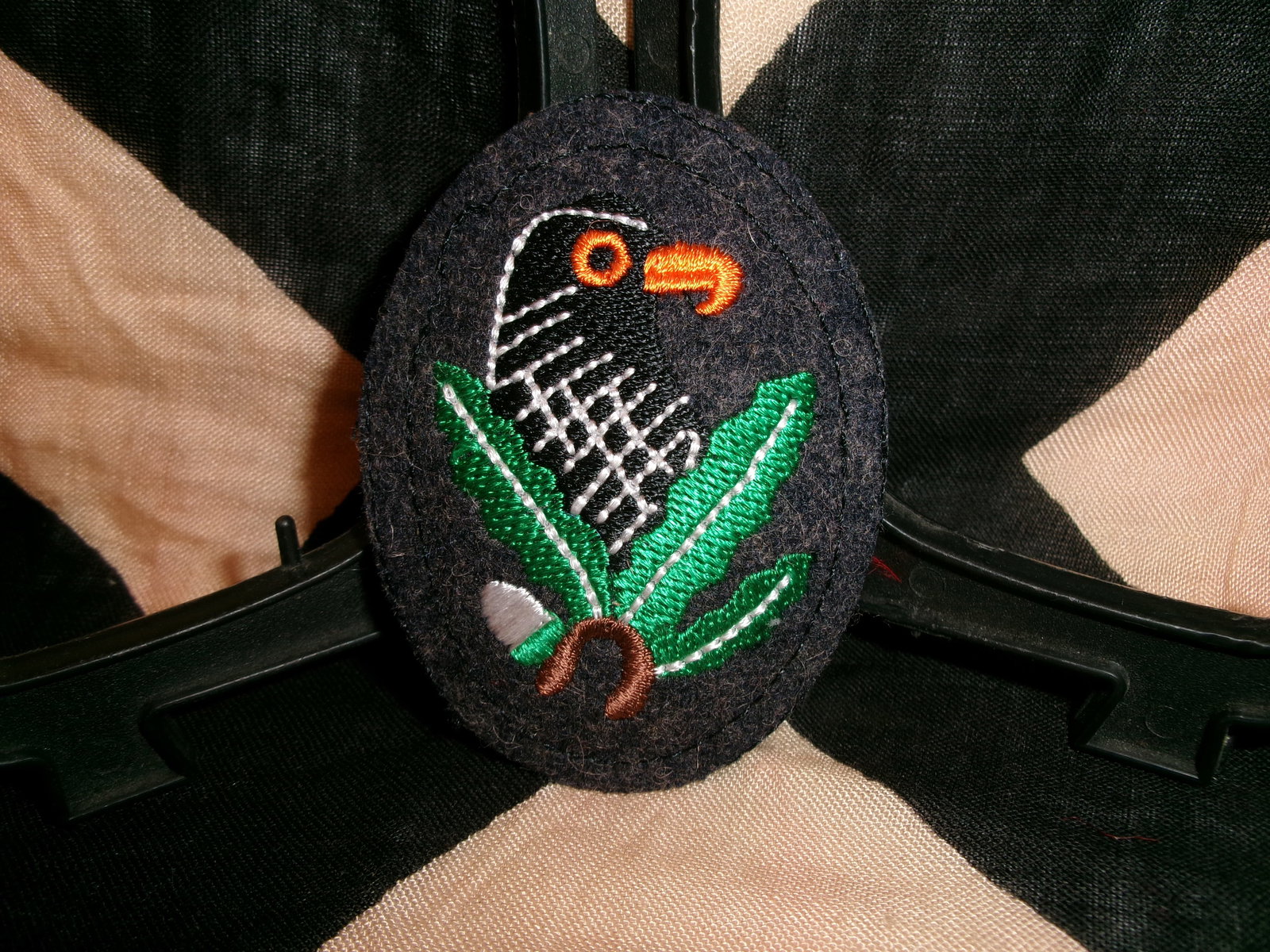 WWII German Hunting / Forestry Sleeve Badge – Embroidered Bird & Oak Leaves: Oval cloth sleeve badge featuring a stylized bird perched above oak leaves and acorns, executed in multi-colored embroidery on a dark wool backing. The design is commonly associated with hunting, fore