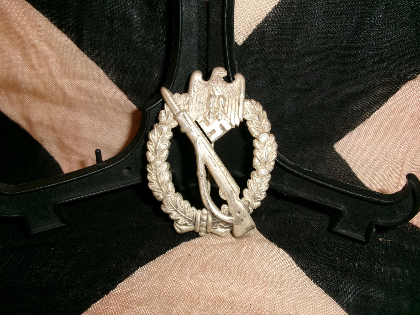 WWII German Infantry Assault Badge (Infanterie-Sturmabzeichen): A metal combat badge depicting a rifle superimposed over an oval oak-leaf wreath, surmounted by a national eagle clutching a swastika. Awarded to German infantry soldiers who participated in multiple 