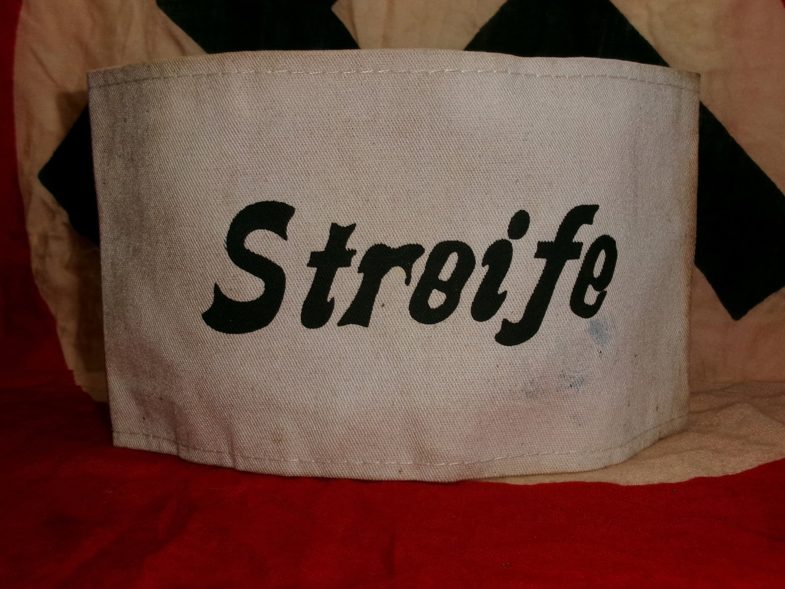 WWII German “Streife?? Armband – White Cloth Patrol Armband with Black Script Lettering: WWII-era German “Streife” (Patrol) armband, constructed from white cloth with bold black script lettering across the front. These armbands were typically worn by personnel assigned to patrol o