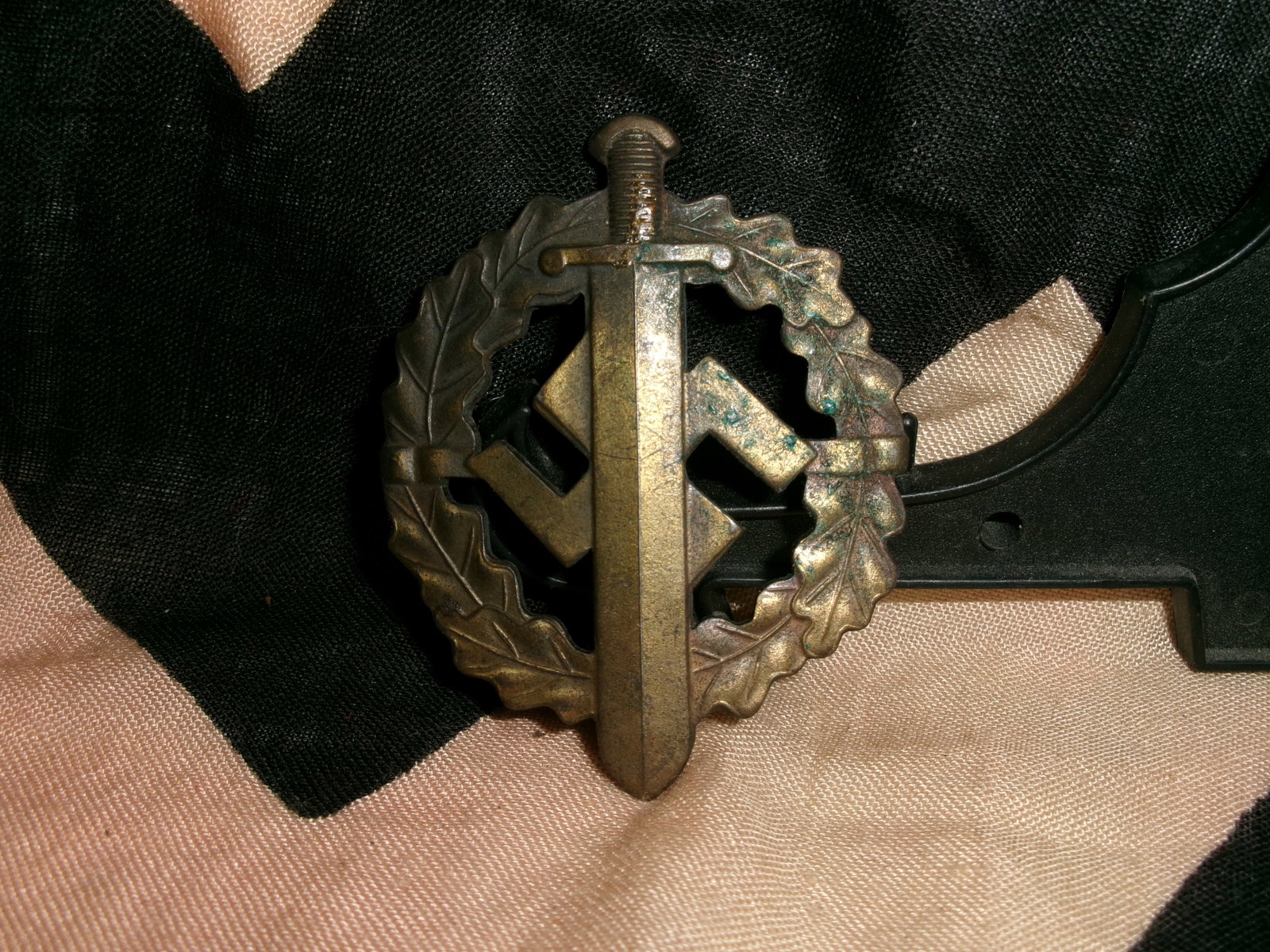 WWII German SA Sports Badge (SA-Sportabzeichen) – Bronze Grade, Sword & Wreath Design: WWII-era German SA Sports Badge (SA-Sportabzeichen) featuring the classic design of a vertical sword overlaid on a swastika, surrounded by an oak leaf wreath. This example appears in a bronze-toned fi