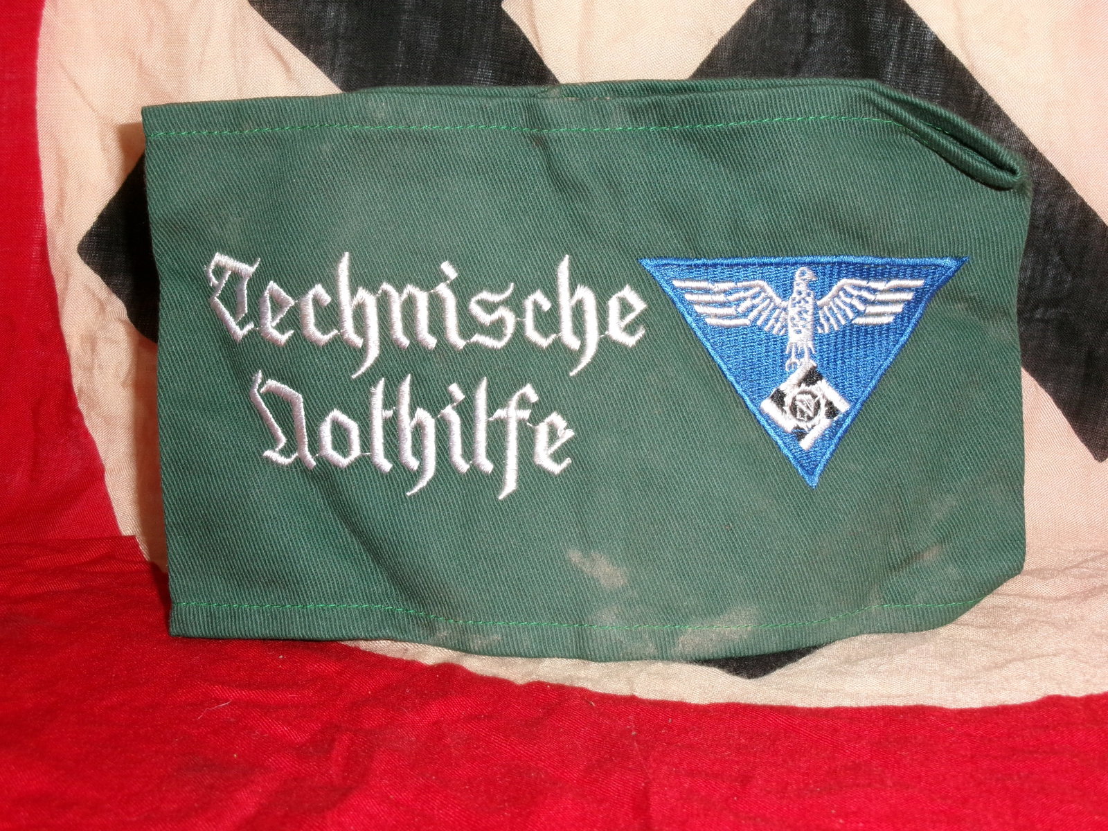 WWII German “Technische Nothilfe?? (Technical Emergency Service) Armband With RZM Paper Tag: This green armband bears the inscription “Technische Nothilfe” (Technical Emergency Service), along with a triangular emblem featuring an eagle and cogwheel motif. The organization was a param