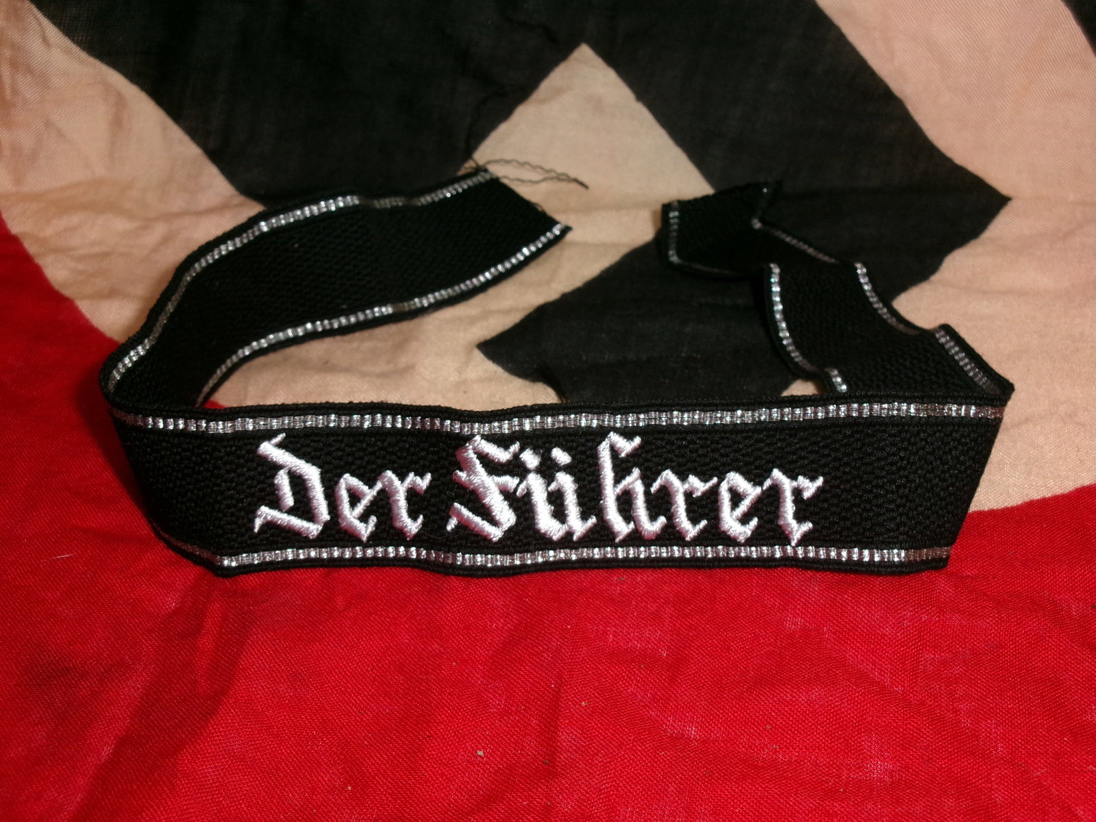 WWII German SS Cuff Title – “Der Führer: This black woven cuff title displays the script “Der Führer” in silver thread, bordered with metallic piping. It was worn on the sleeve of SS uniforms to denote affiliation with the SS-Standa