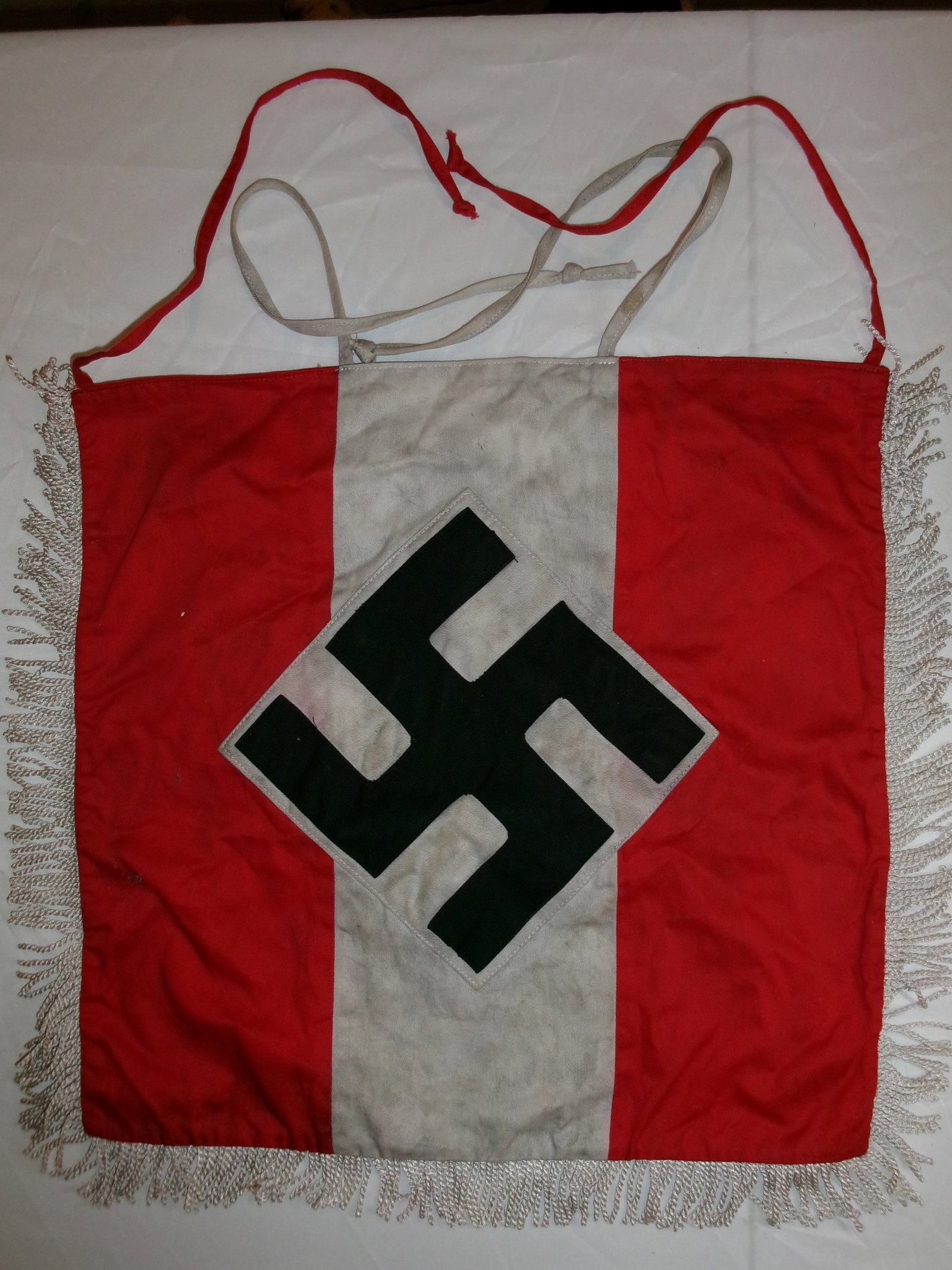 WWII German Hitler Youth Banner with RZM Tag (HJ Organizational Pennant): A cloth banner associated with the Hitlerjugend (Hitler Youth), featuring the characteristic red field with a central vertical white panel and a black swastika set within a white diamond. The banner i