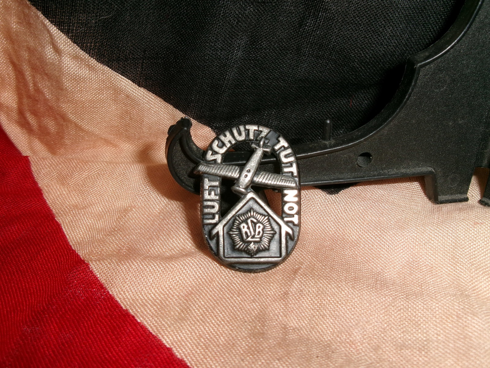WWII Reichsluftschutzbund “Luftschutz Tut Not?? Donation Pin: Metal badge associated with the Reichsluftschutzbund (RLB), Germany’s civil air defense organization during WWII. It displays the phrase “Luftschutz Tut Not” (“Air protection is necessary&