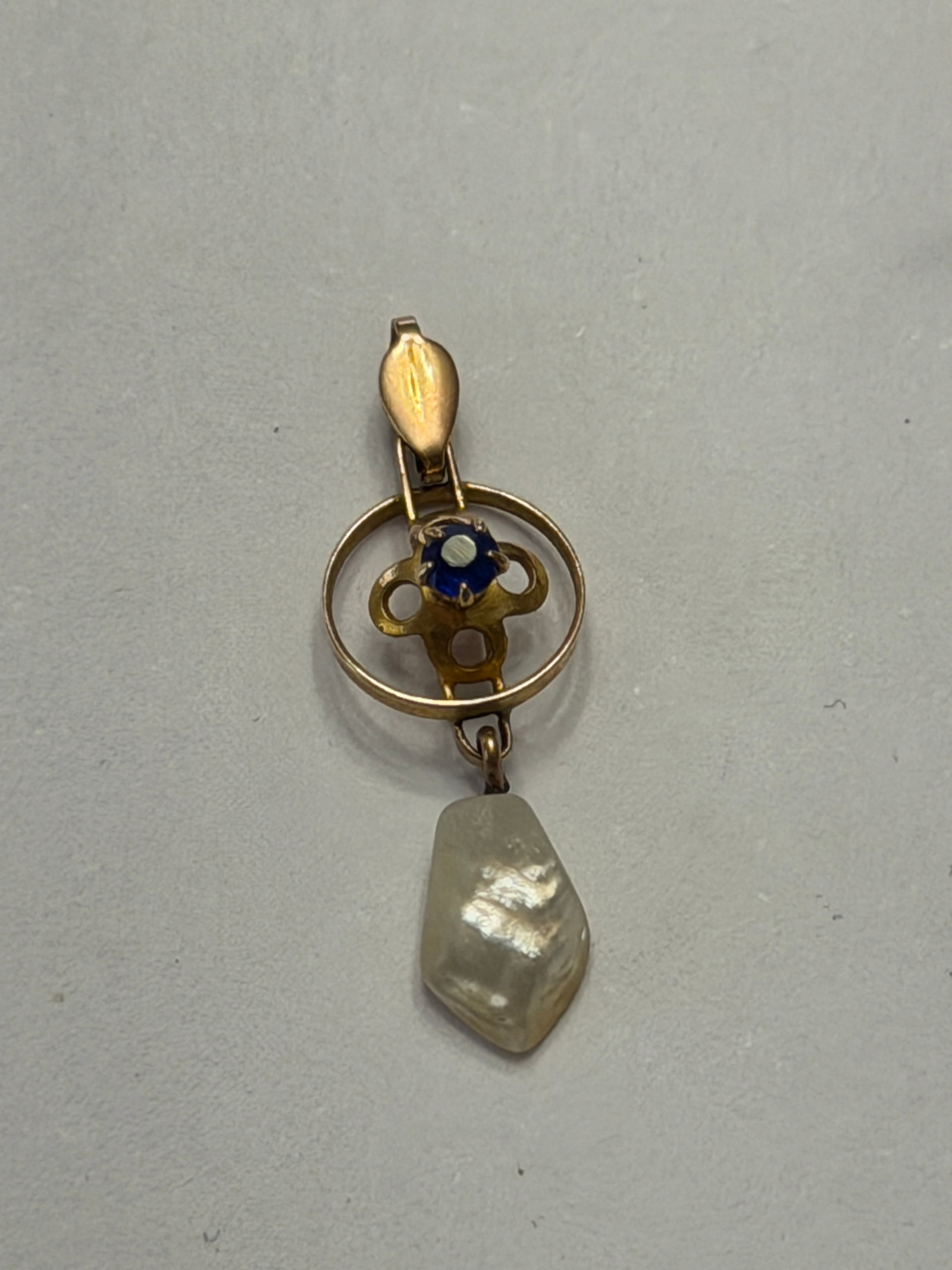 Victorian Style 10K Gold Pearl & Sapphire Pendant: Charming Victorian-style pendant crafted in warm 10K gold, featuring a delicate openwork design accented with a deep blue sapphire at the center. Suspended below is an irregularly shaped natural pearl