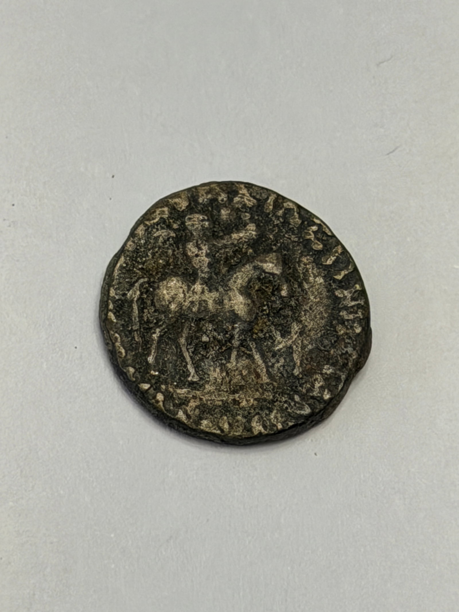 Ancient Roman Coin – Horseman Reverse & Standing Figure (Worn Circulated Example): Roman coin featuring a heavily worn but still recognizable design. One side shows a mounted horseman, likely symbolizing military strength or imperial authority. The opposite side depicts a standing f