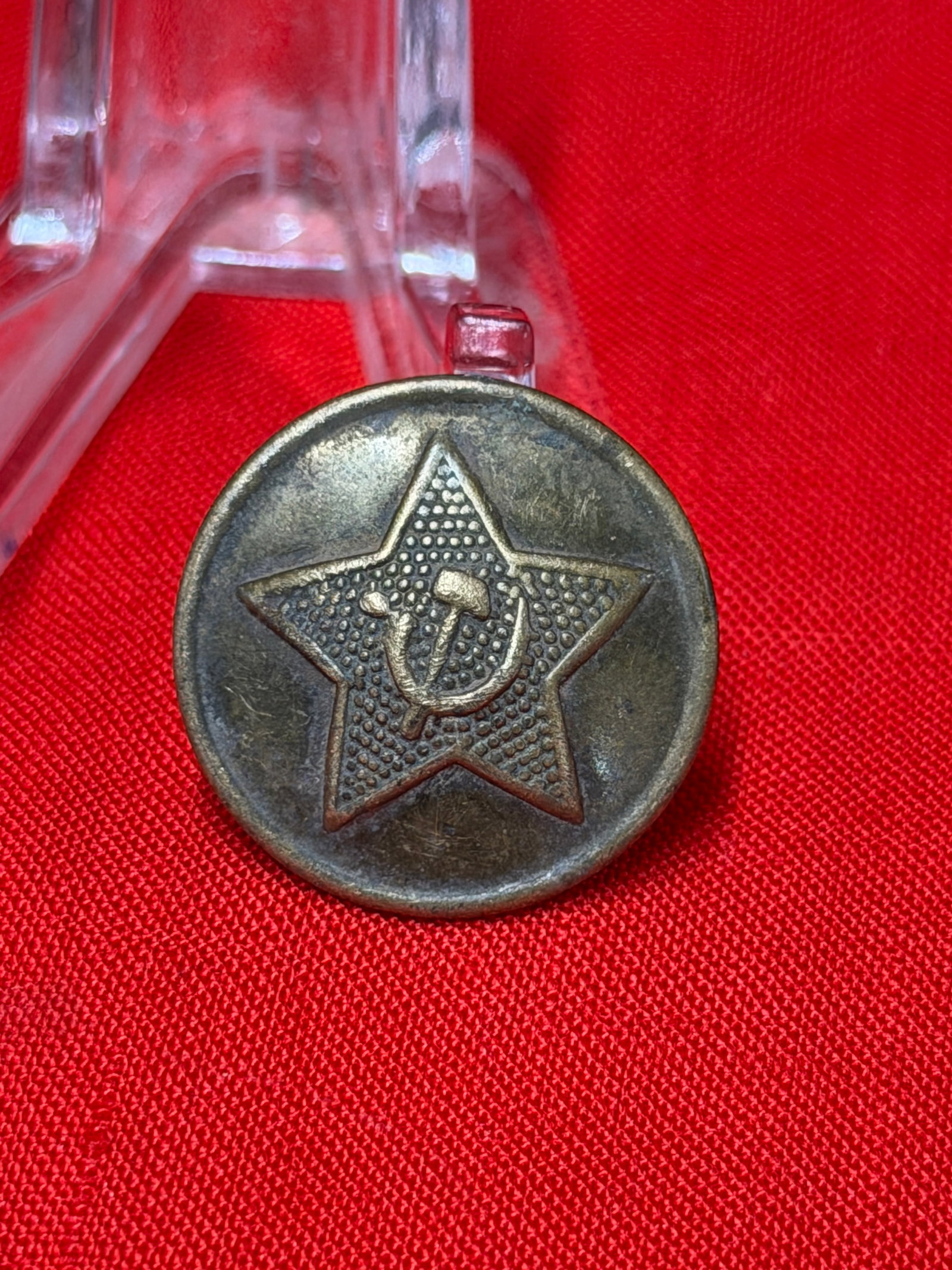 WW2 Soviet Red Army Star Uniform Button with Hammer & Sickle Emblem: WW2 era Soviet Red Army uniform button featuring a raised five-point star with central hammer and sickle emblem against a textured background. The reverse retains its original hook-style attachment an